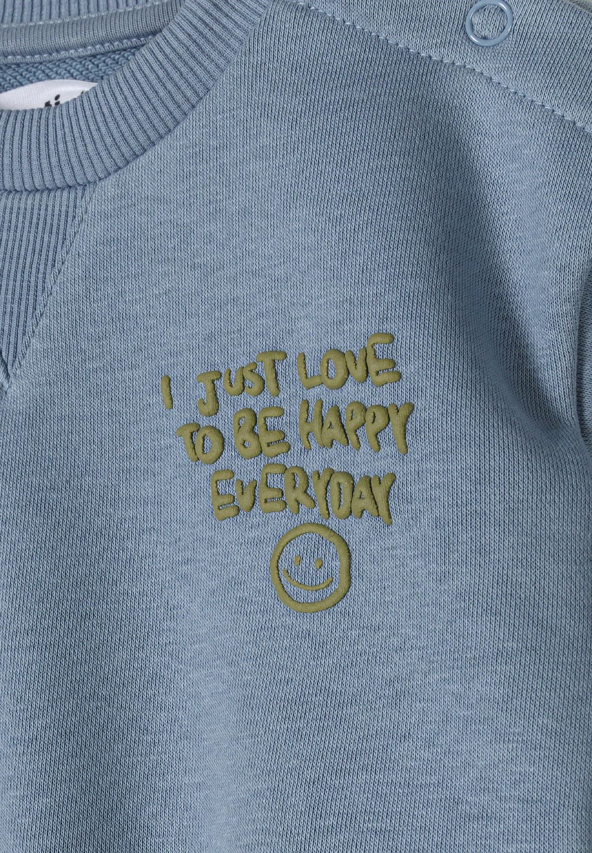 Detail of blue boys sweatshirt with embroidered text and smiley face.