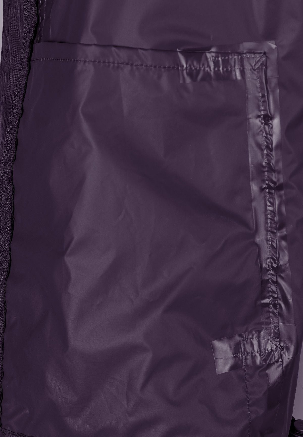 Detail of a purple waterproof jacket with a zip pocket and overlapping pleat.