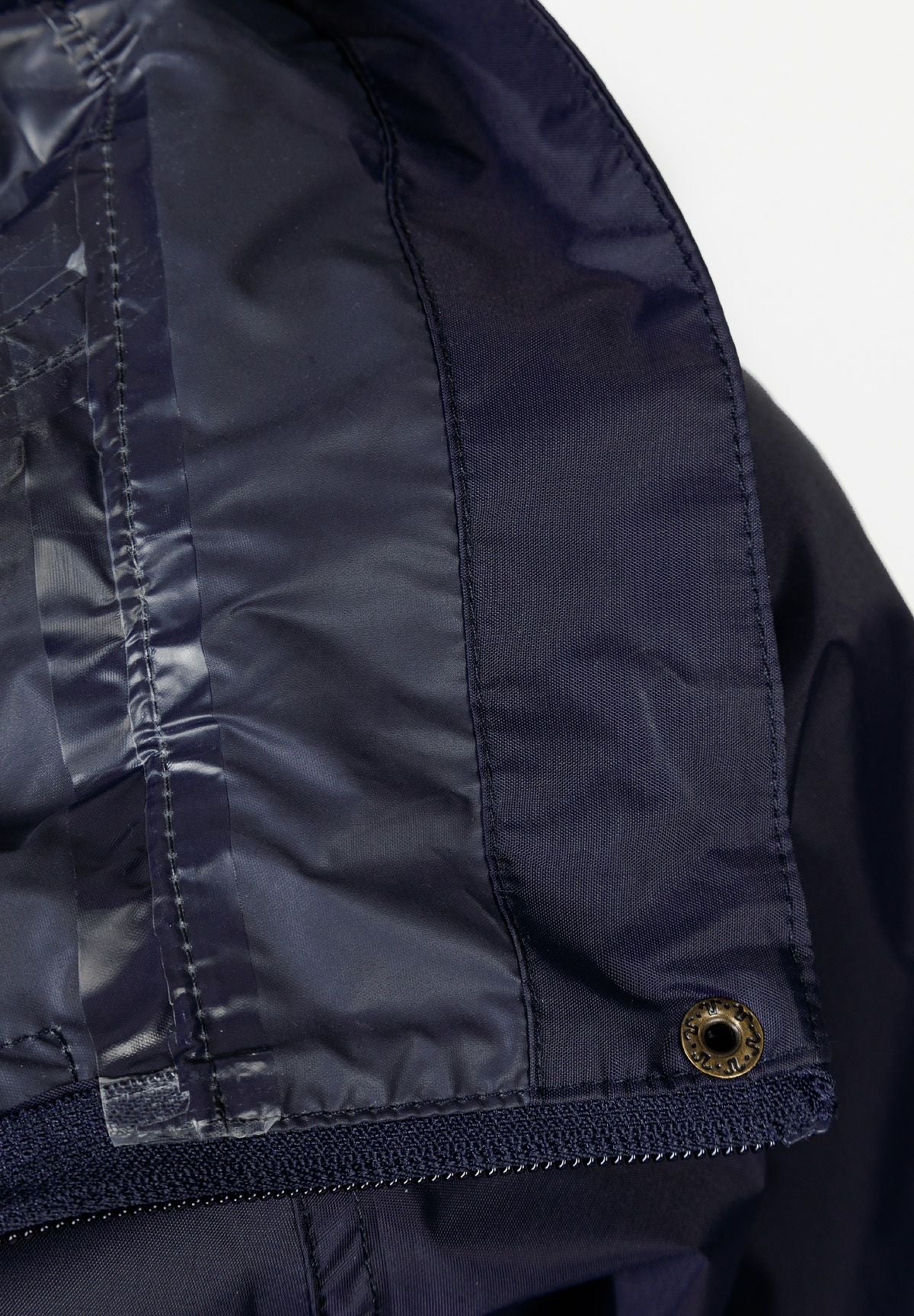 Detail of navy waterproof jacket showing concealed hood and zip fastening.