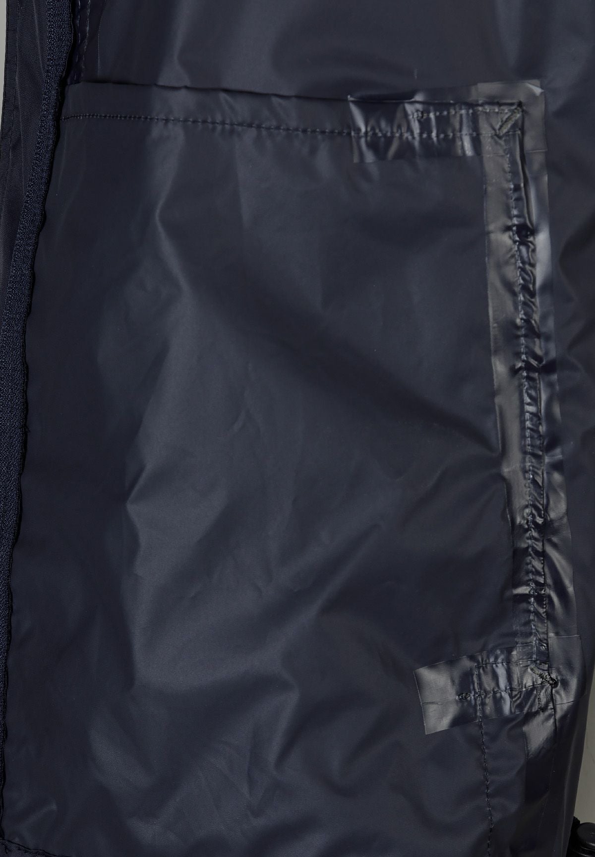 Detail of a navy waterproof jacket showing a zipped pocket and seam.