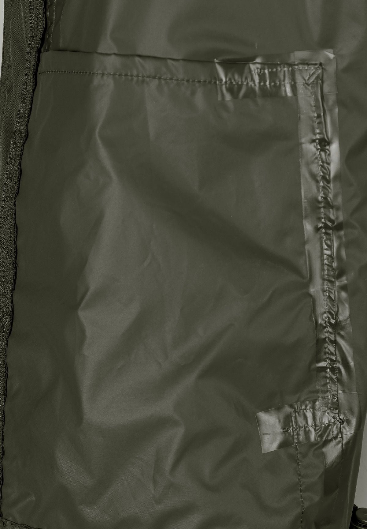 Detail of a khaki waterproof jacket showing a zip pocket and seam.