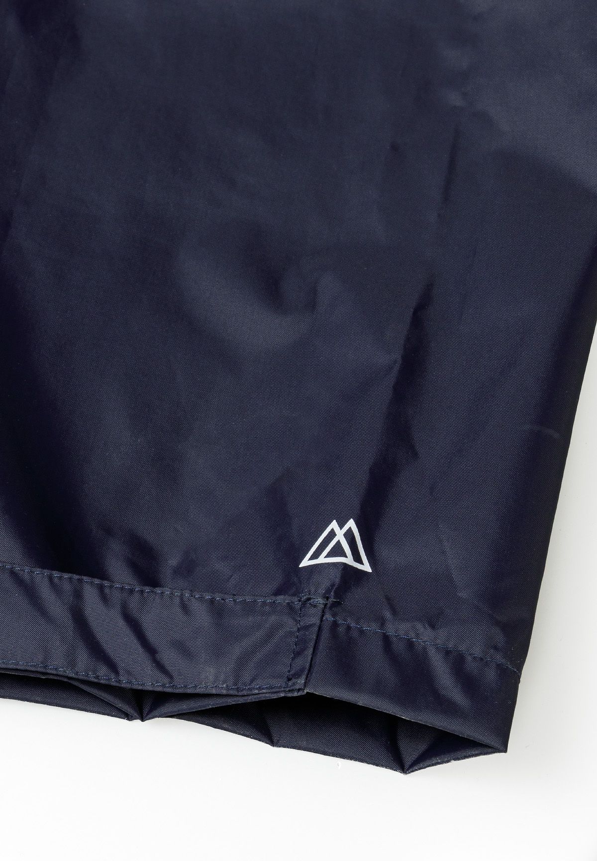 Close-up of navy waterproof overpants with adjustable velcro fastenings and logo.