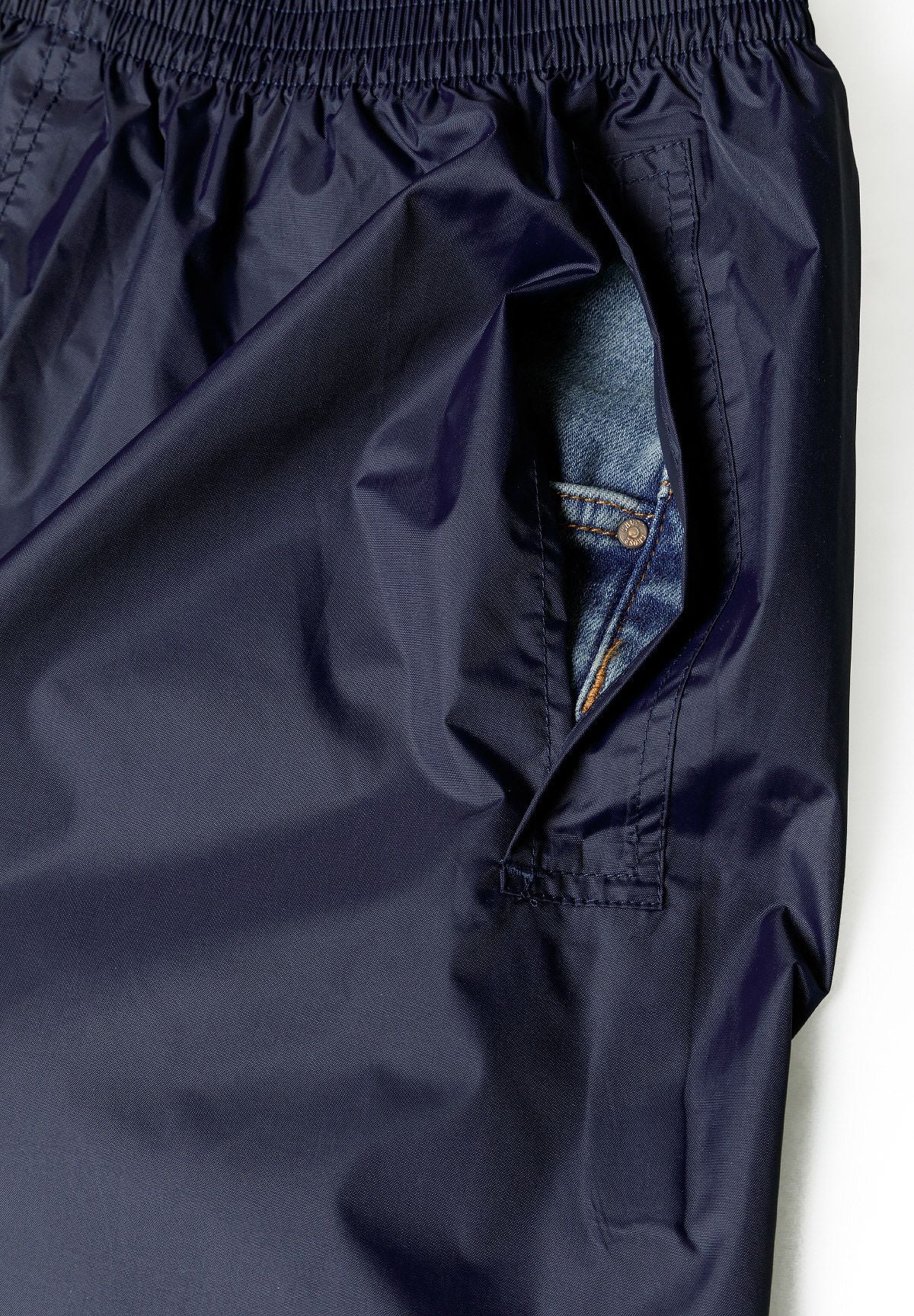 Detail of navy waterproof overpants with elastic waistband and side pocket access.