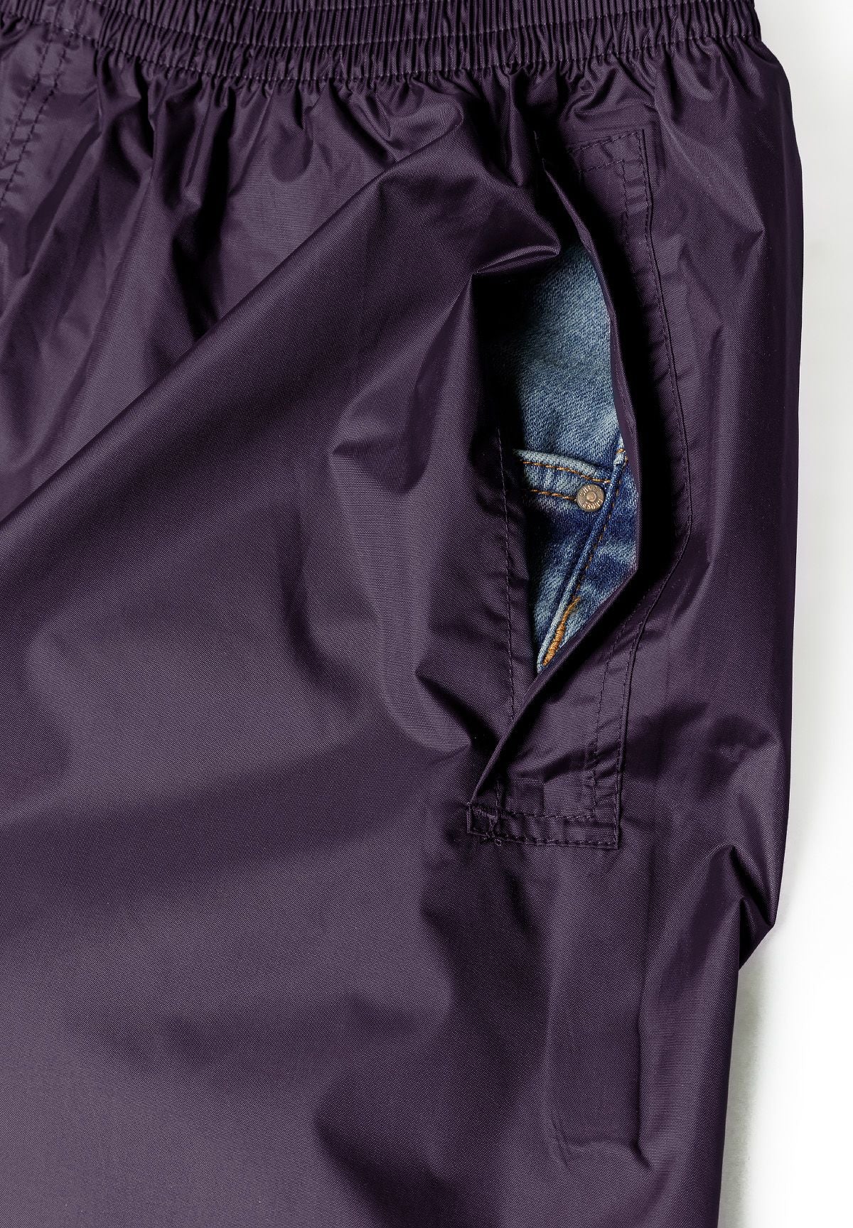 Detail of women's purple packaway waterproof overpants with side pocket access.