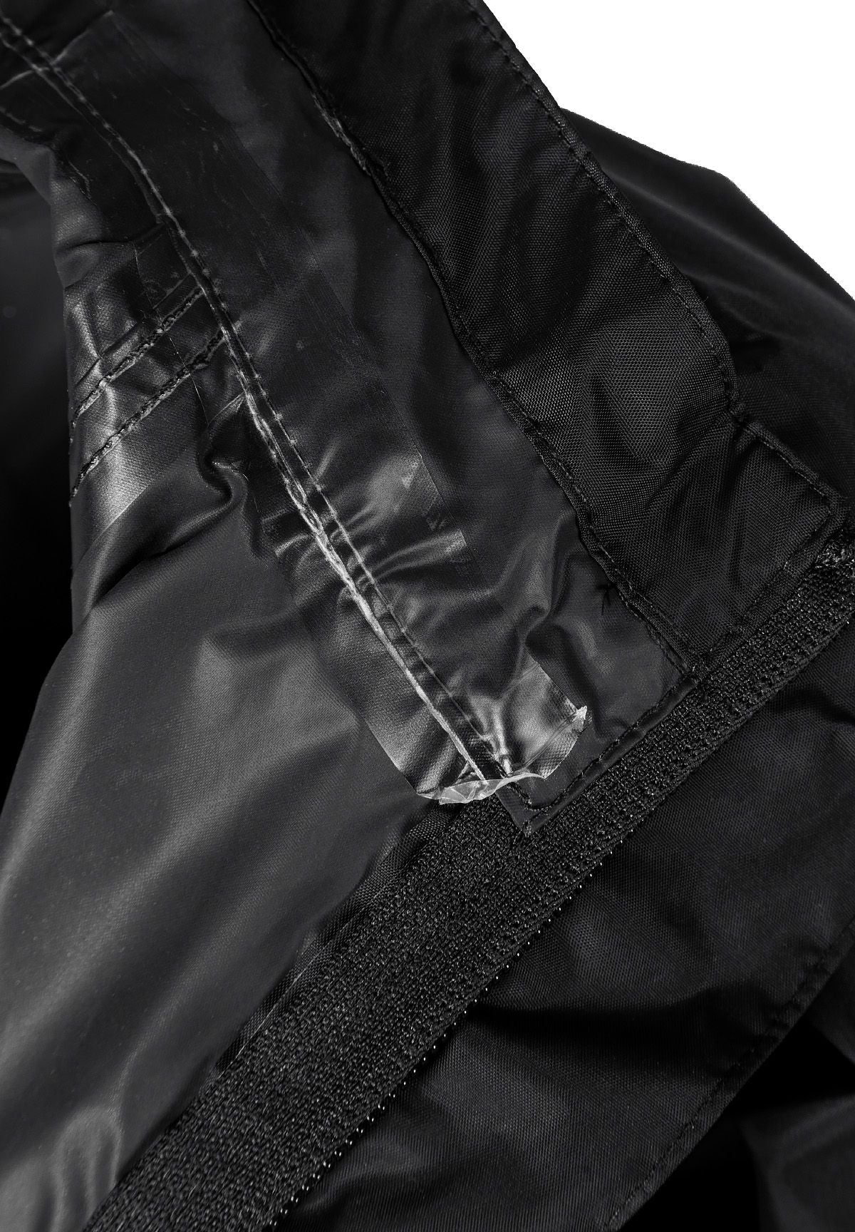 Detail of a black waterproof jacket showing the inner lining and velcro closure.