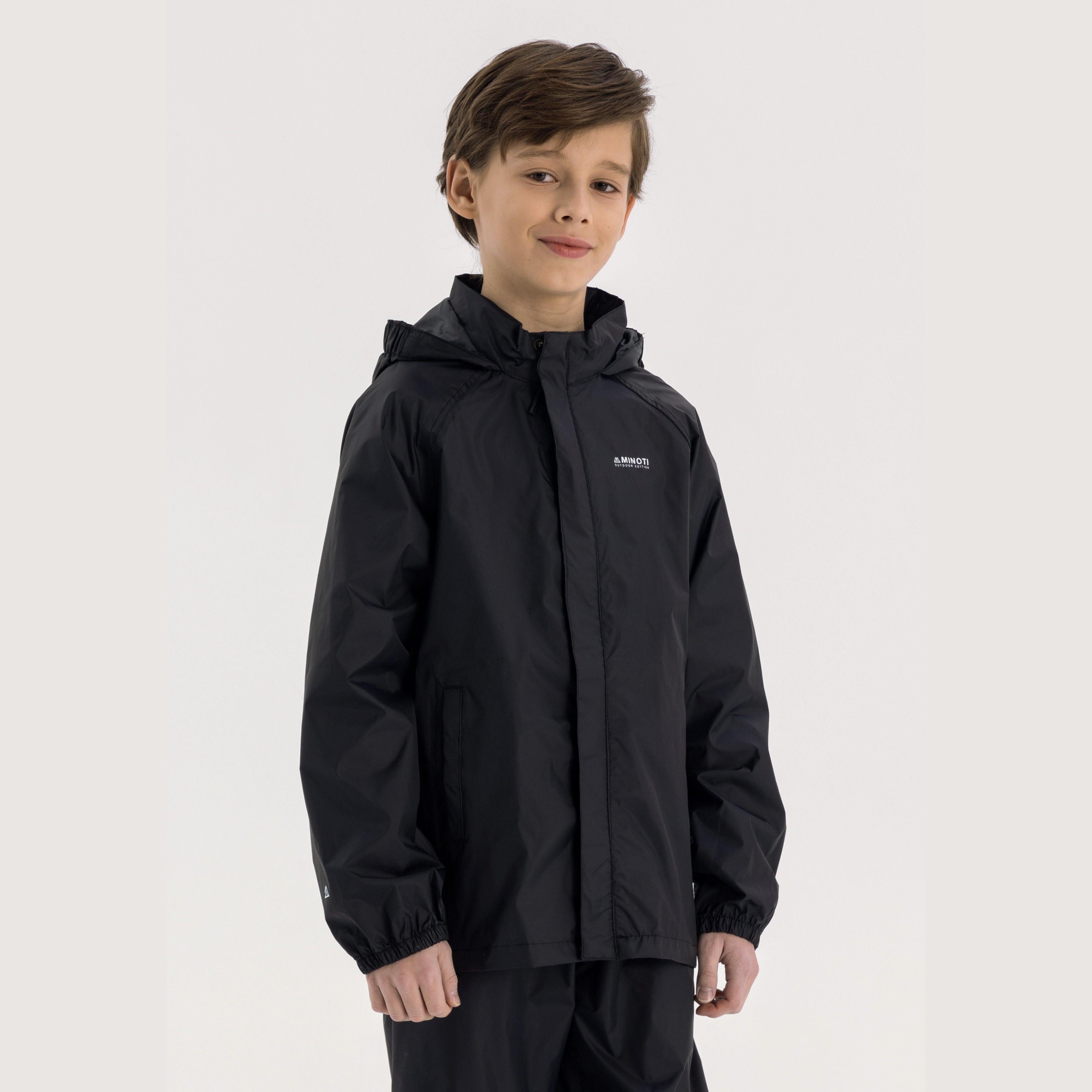 Boy in black hooded waterproof jacket pointing forward, wearing light blue cargo jeans and black sneakers on white studio background