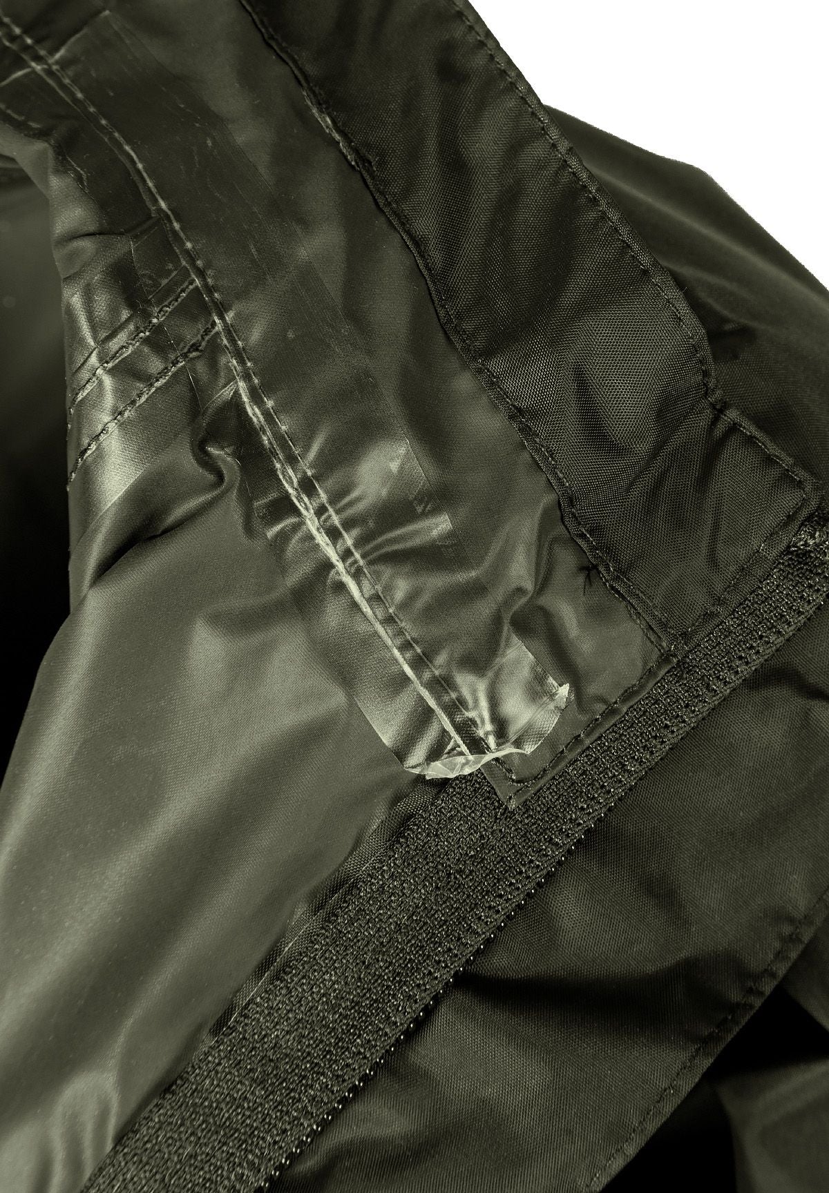 Detail of a khaki kids waterproof jacket showing the interior seam and velcro.