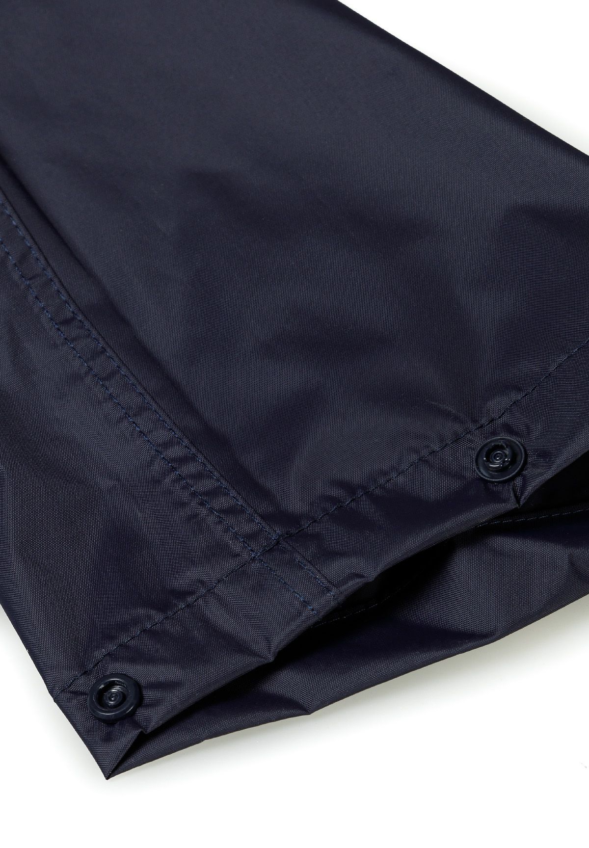 Detail of navy waterproof overpants with button closure and elasticated ankle cuffs.