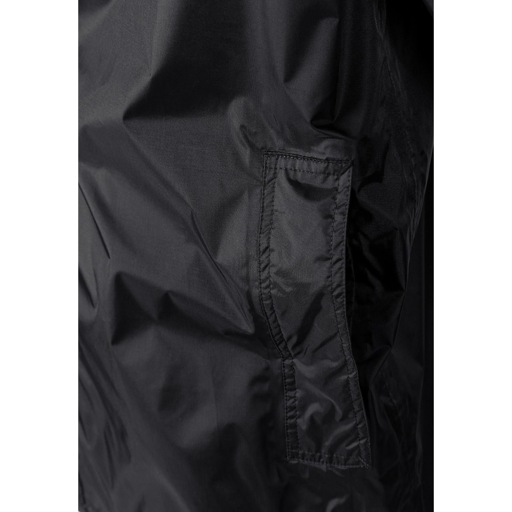 Close-up detail of black waterproof jacket interior showing taped seams and zip construction for weather protection