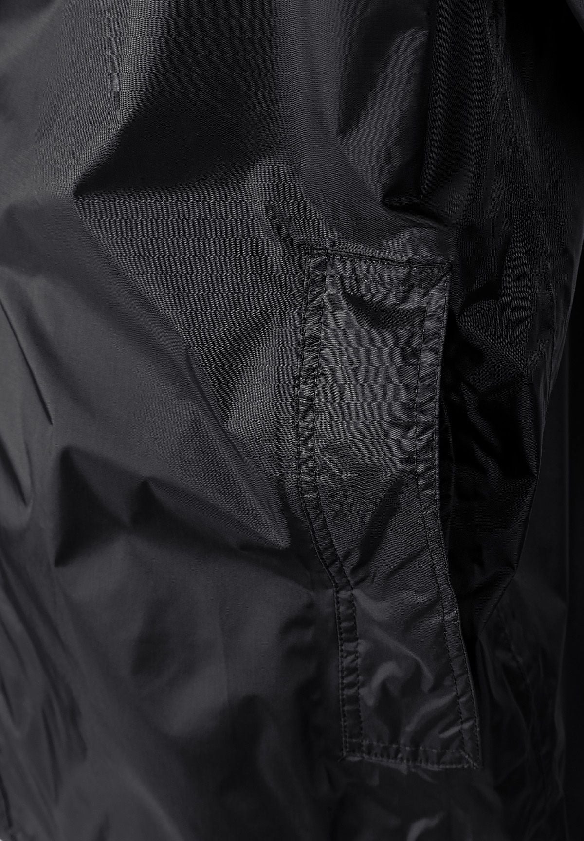 Detail of a black men's waterproof jacket showing a zipped pocket.