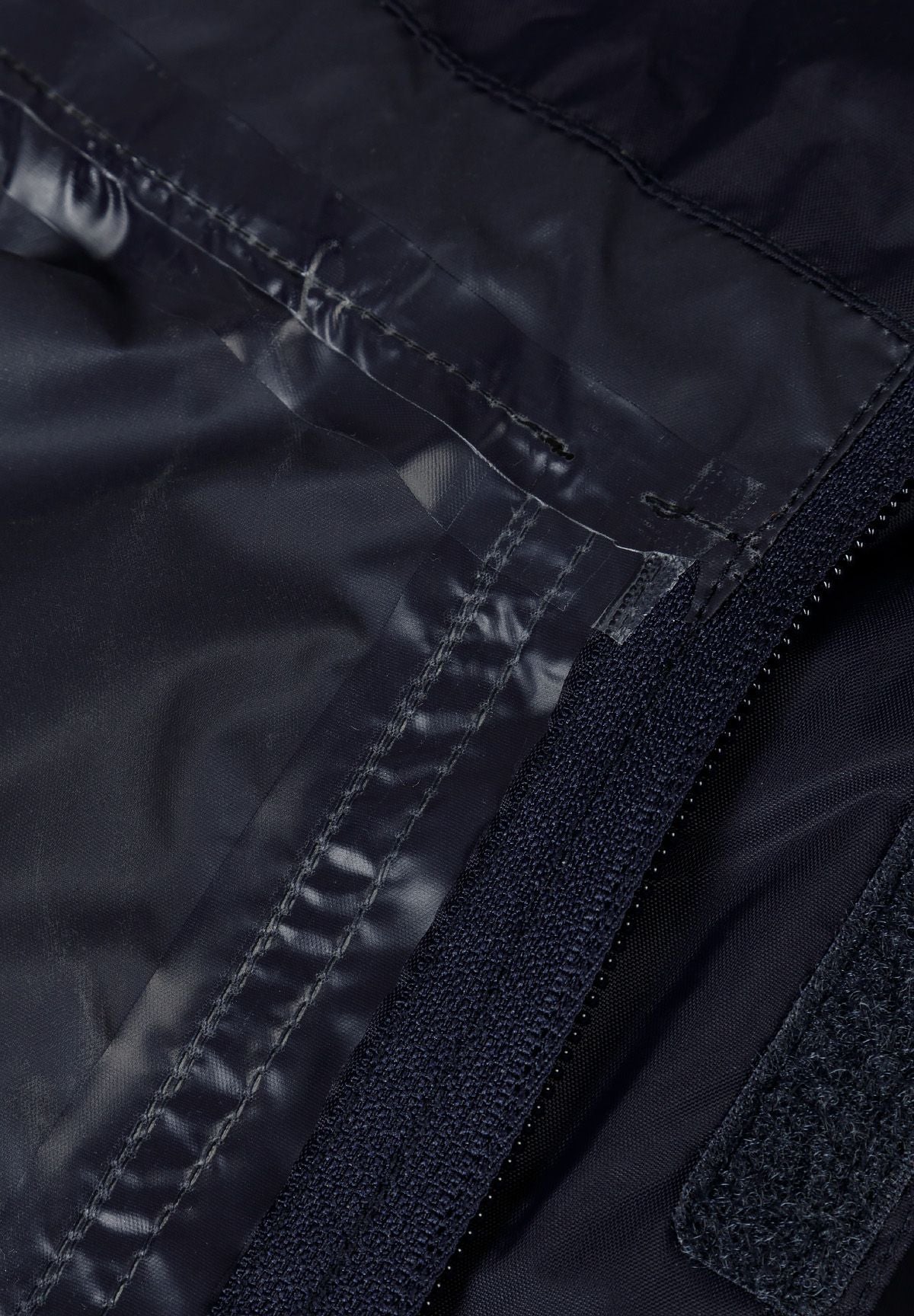 Detail of a navy waterproof jacket showing zipper and fabric texture.