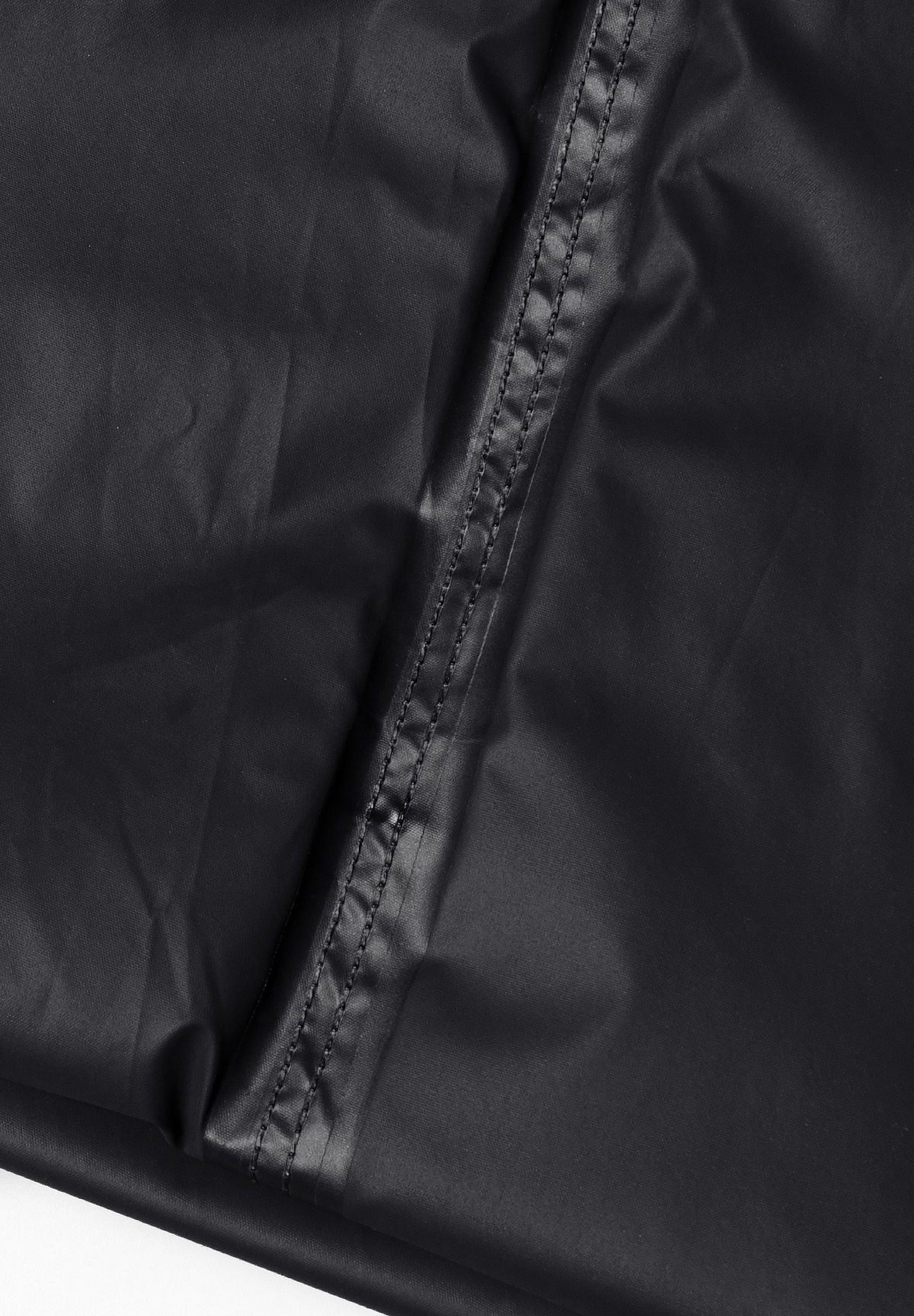 Detail of black waterproof overpants with visible stitching.