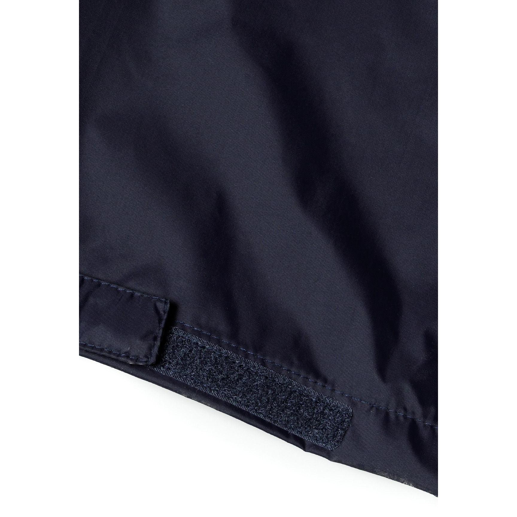 Close-up detail of navy waterproof overpants showing velcro adjustable cuffs and inner blue fabric lining at leg opening