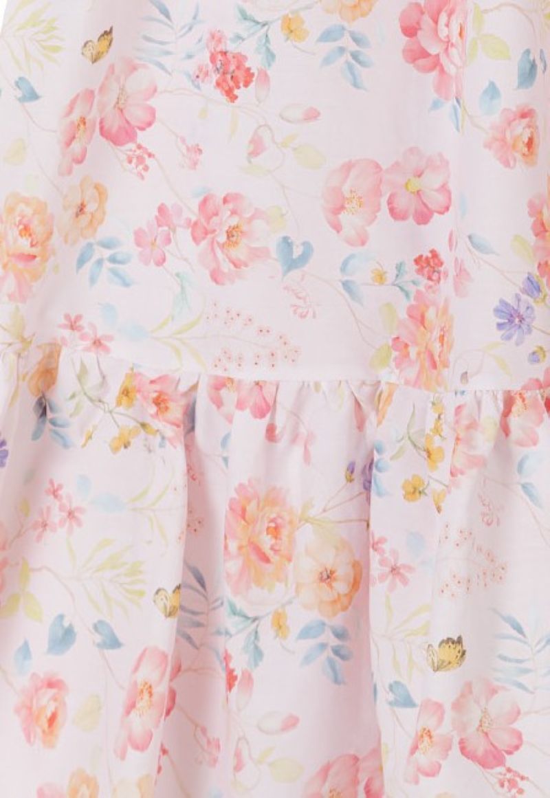 Close-up of pink sundress fabric with peach and lilac flowers above the gathered hem tier.