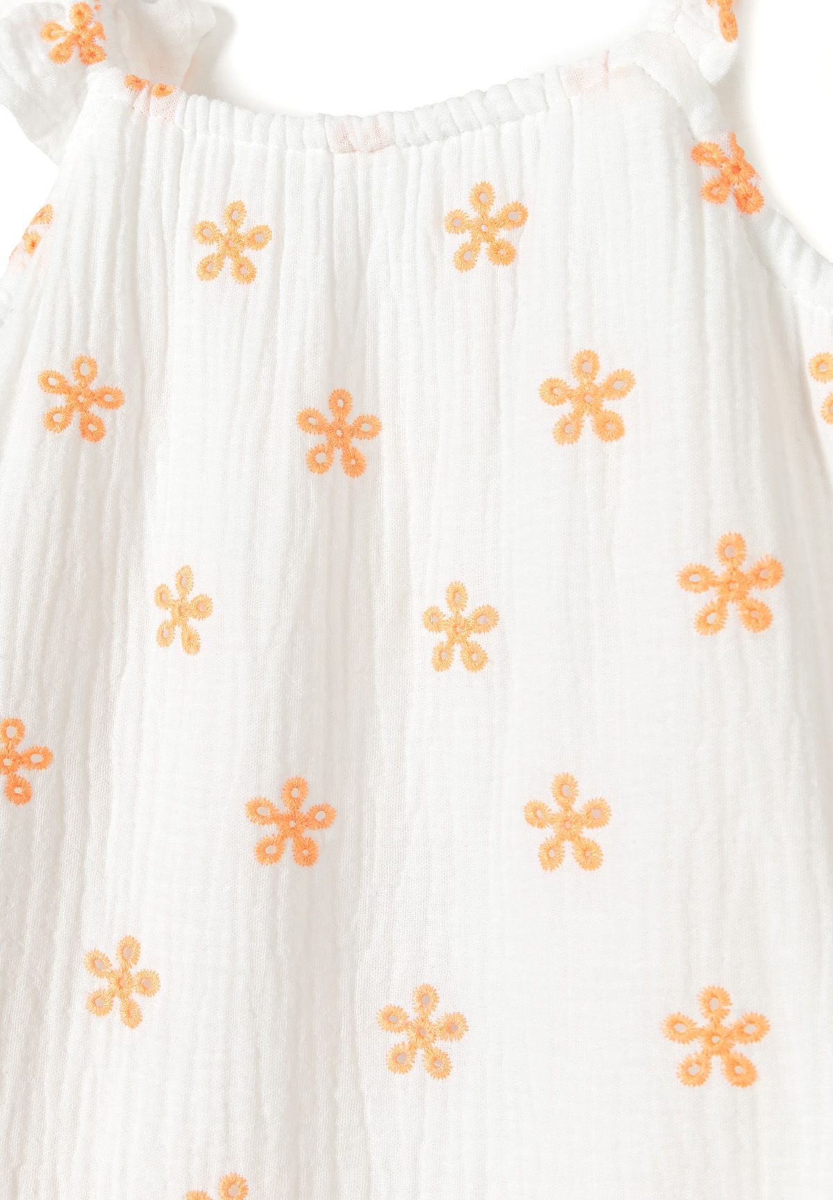 Close-up of white sundress fabric with orange embroidered flowers, fine vertical crinkles and a gathered neckline.