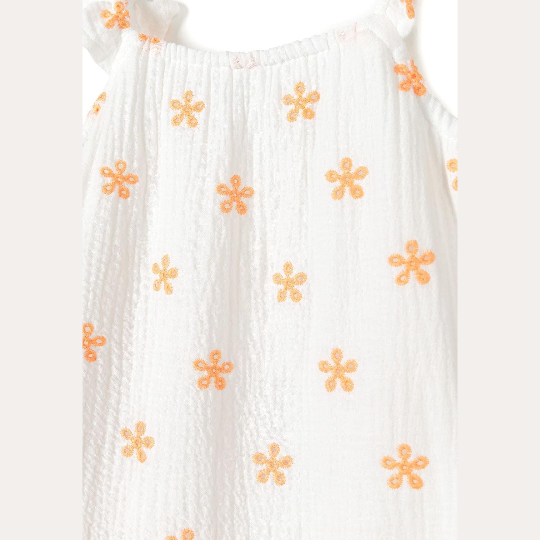Close-up detail of white cotton muslin fabric showing orange floral embroidery pattern and texture of the breathable muslin weave