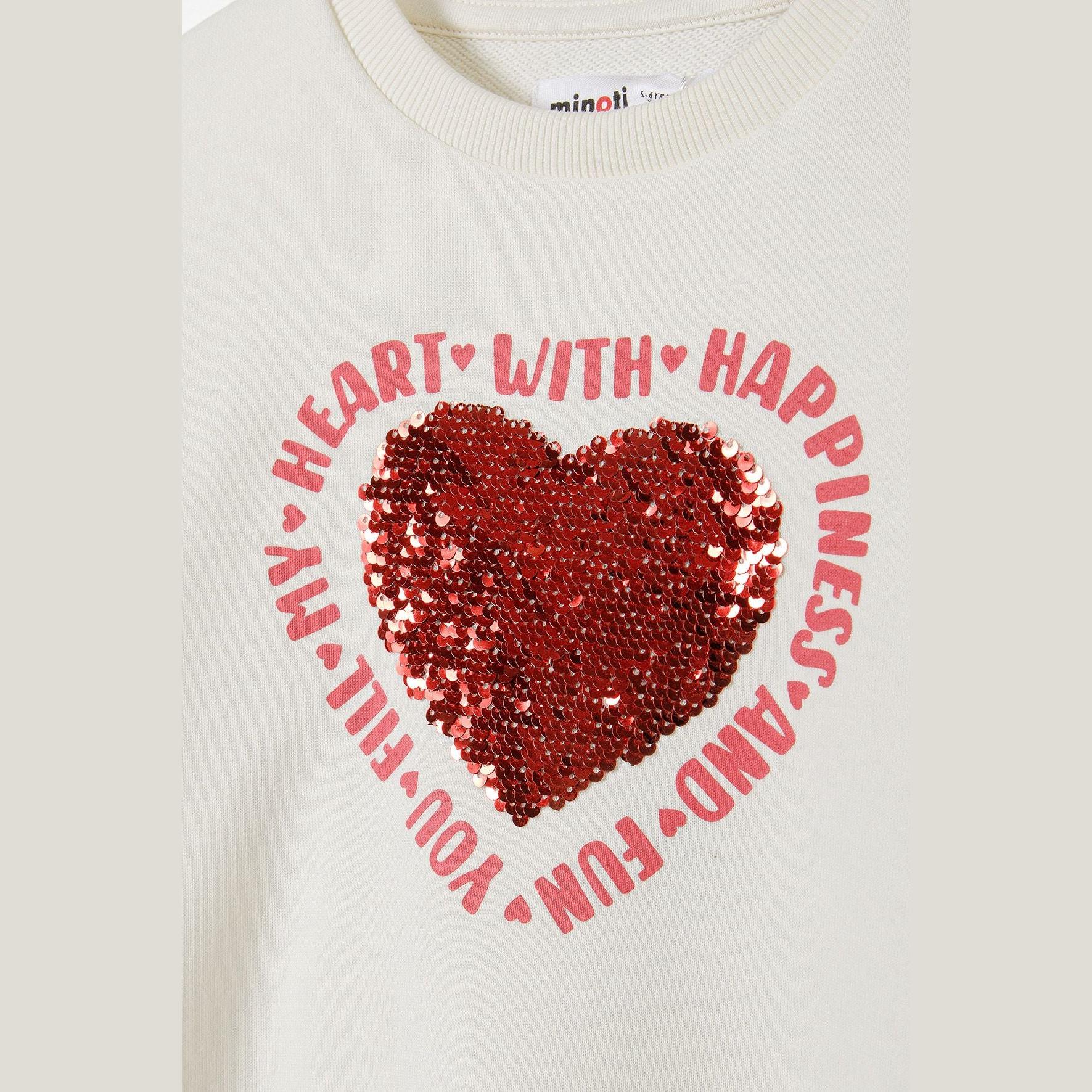 Close-up detail of red sequin heart motif surrounded by 'Heart With Happiness' text on cream sweatshirt, showing Minoti label