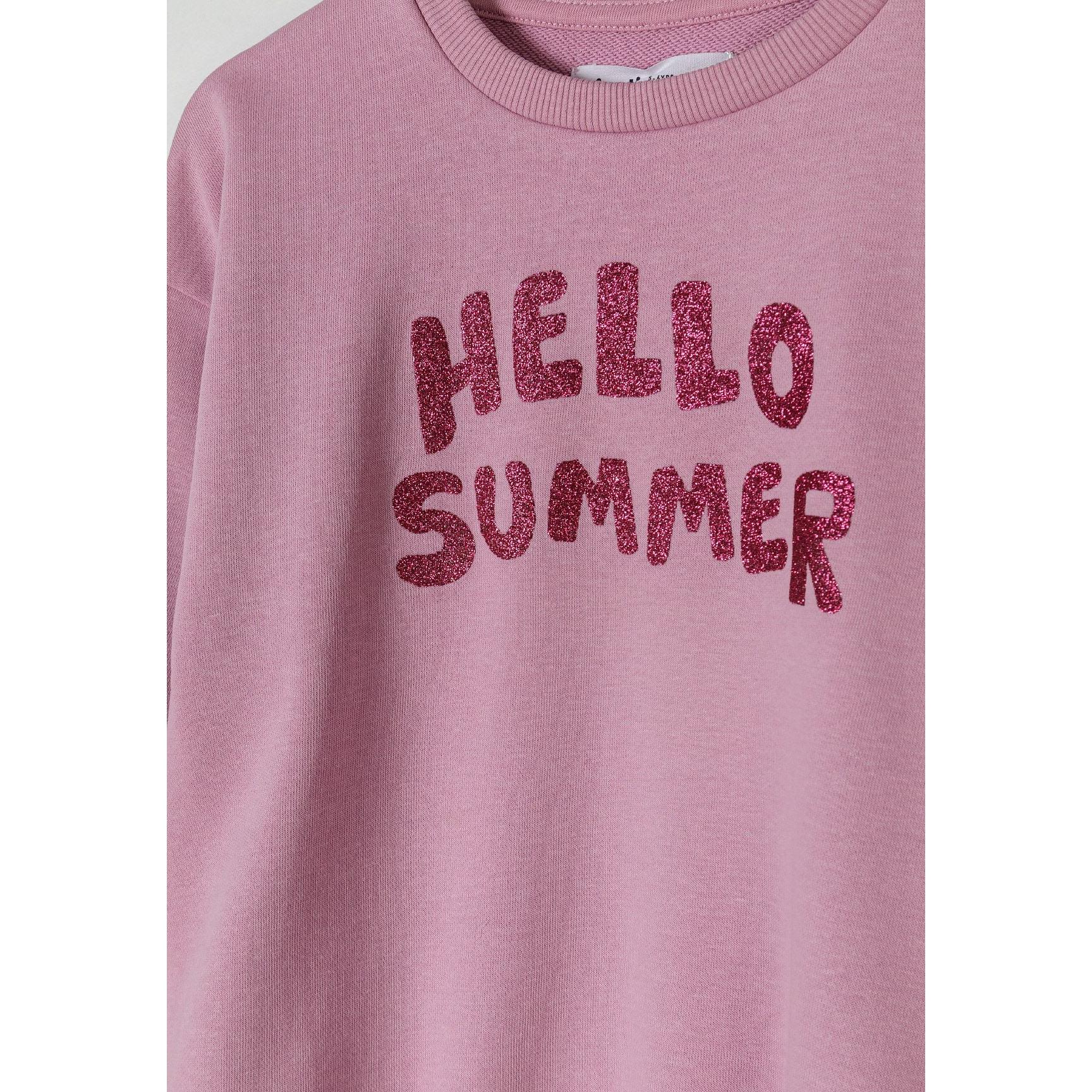 Close-up detail of sparkly red Hello Summer text print on lilac fleece sweatshirt fabric showing texture and glitter effect