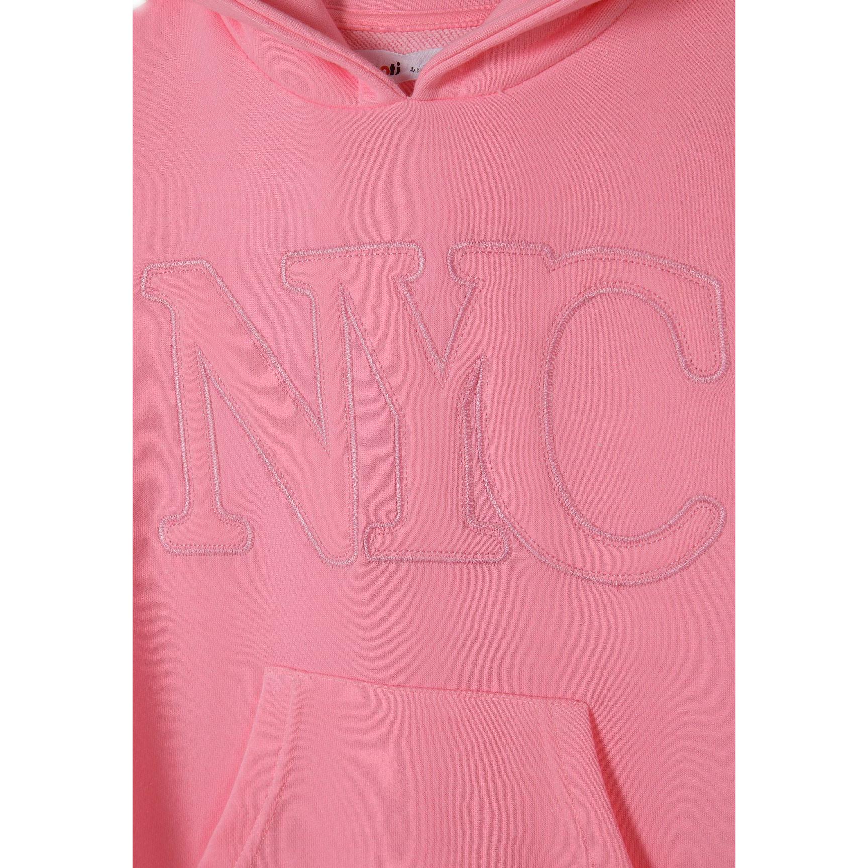 Close-up detail of embroidered NYC lettering and kangaroo pocket on pink cotton fleece hooded dress