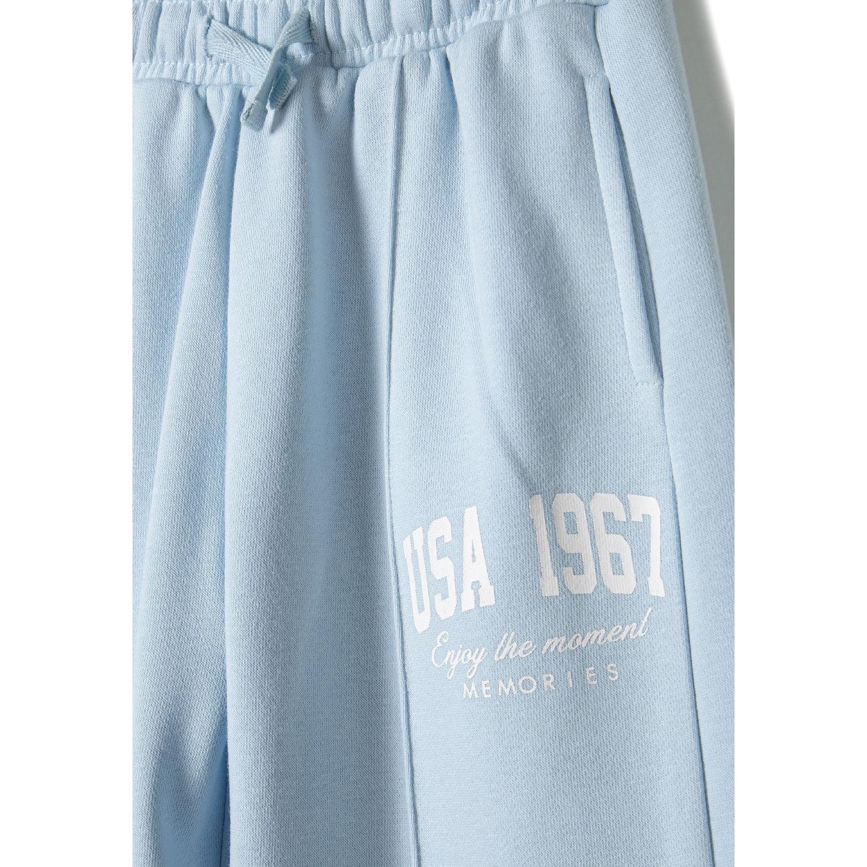 Close-up detail of light blue wide leg joggers showing elastic waistband with drawstring and white USA 1967 text print