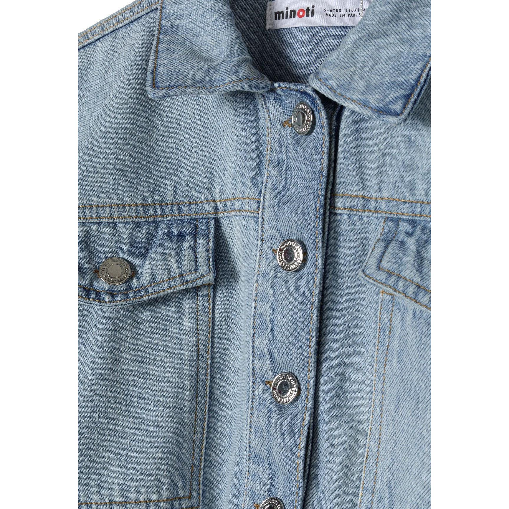 Close-up detail of light blue denim jacket showing Minoti label, collar, button closure and chest pocket construction