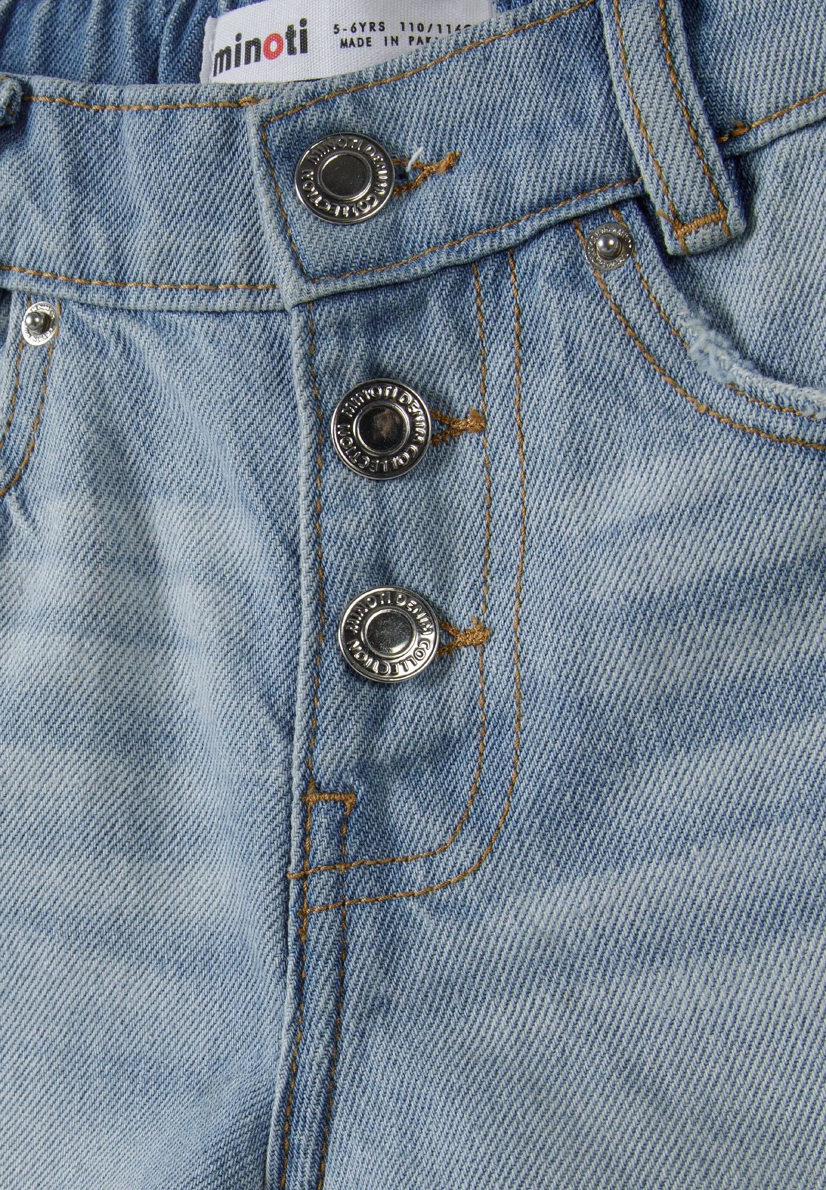 Detail of light blue denim shorts featuring button fastening and frayed hem.