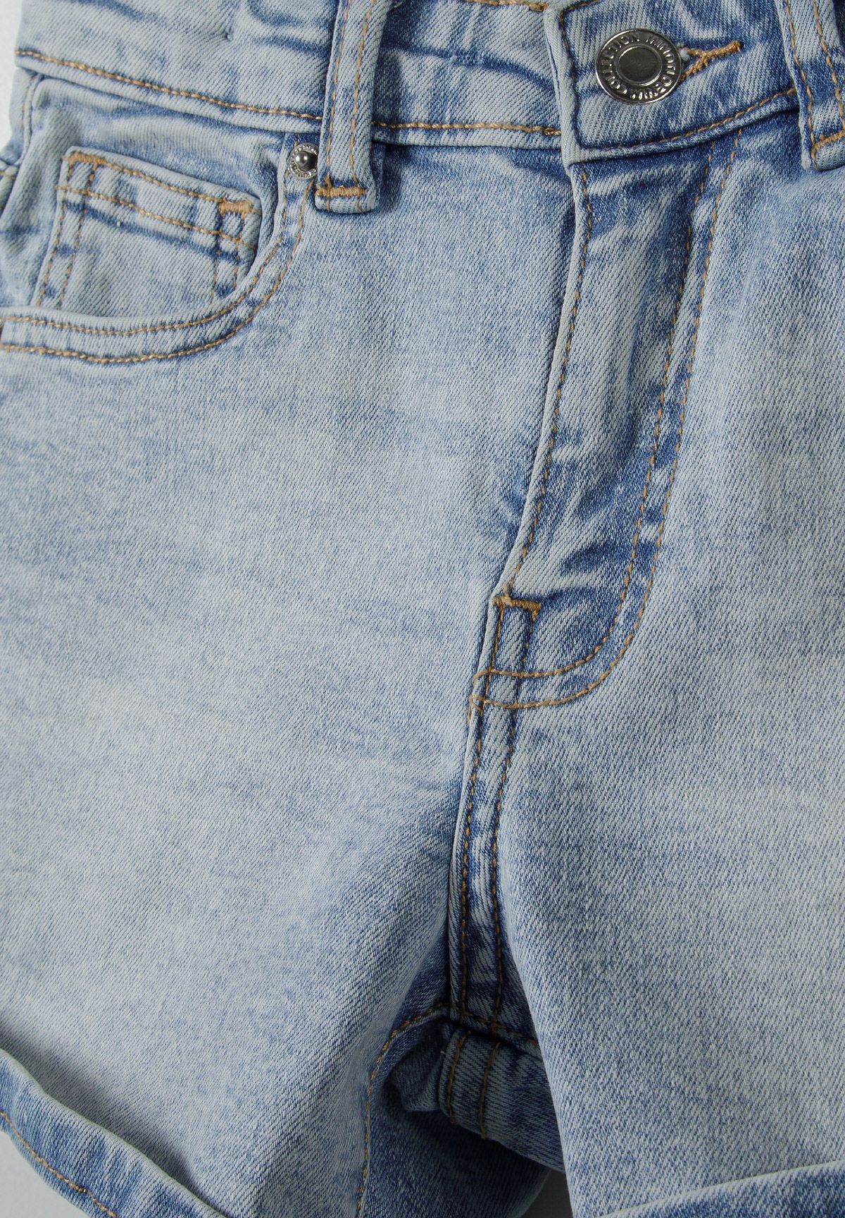 Detail of girls high waist light blue denim shorts with stitched cuffs and front zip.