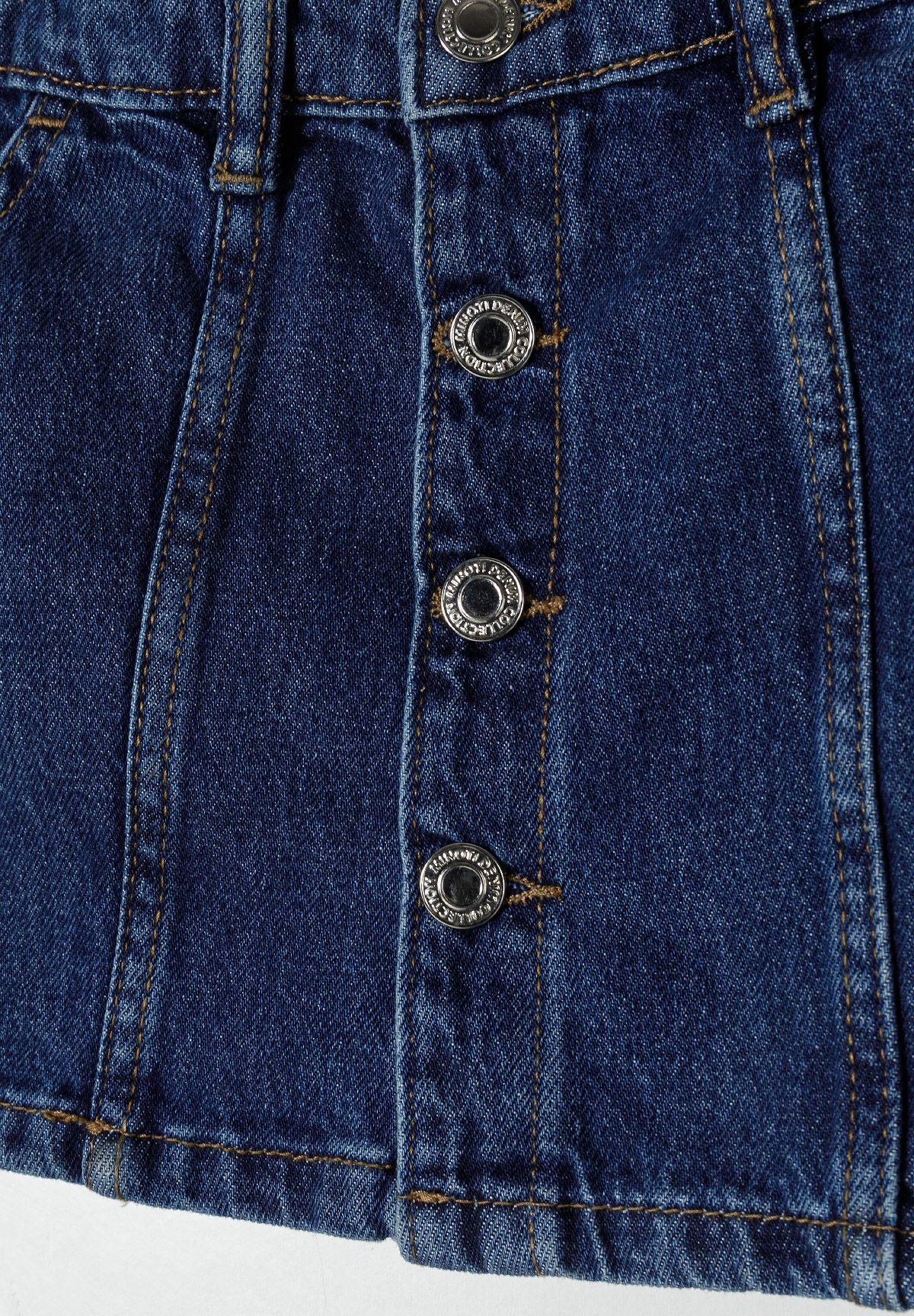 Detail of girls denim skirt with button fastening and front pockets.