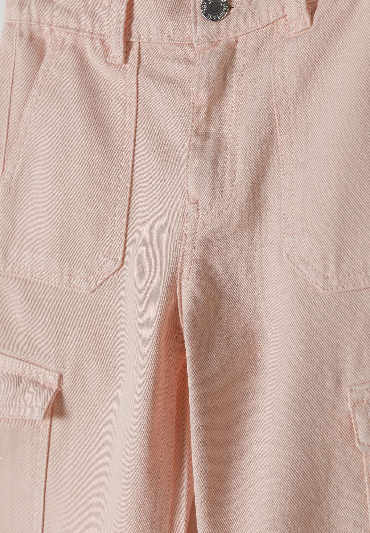 Detail of girls wide leg cargo trousers in soft pink with front pockets and button fastening.