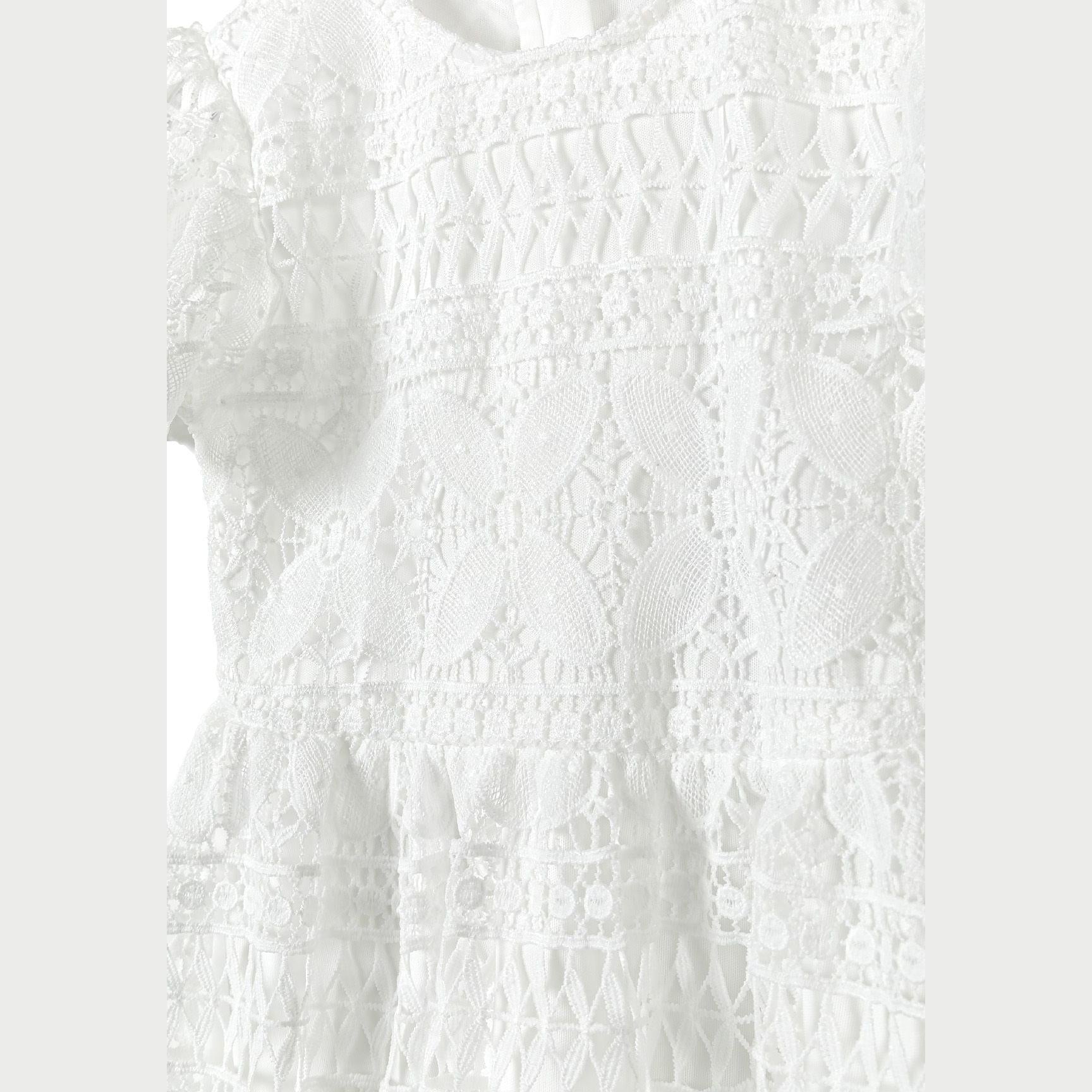 Close-up detail of white lace fabric showing intricate floral patterns and textural elements of the dress