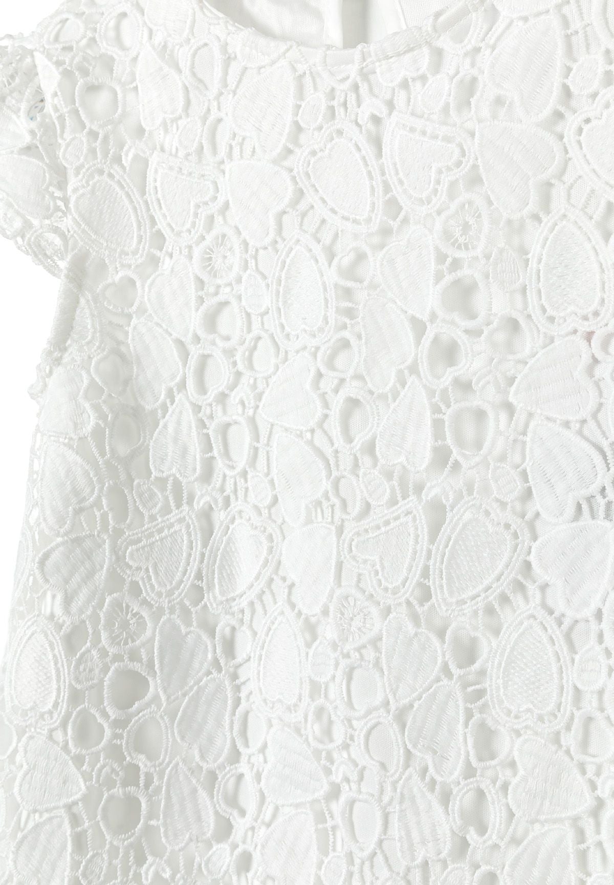 Detail of a girls' white lace dress featuring intricate lace patterns on the bodice and sleeves.