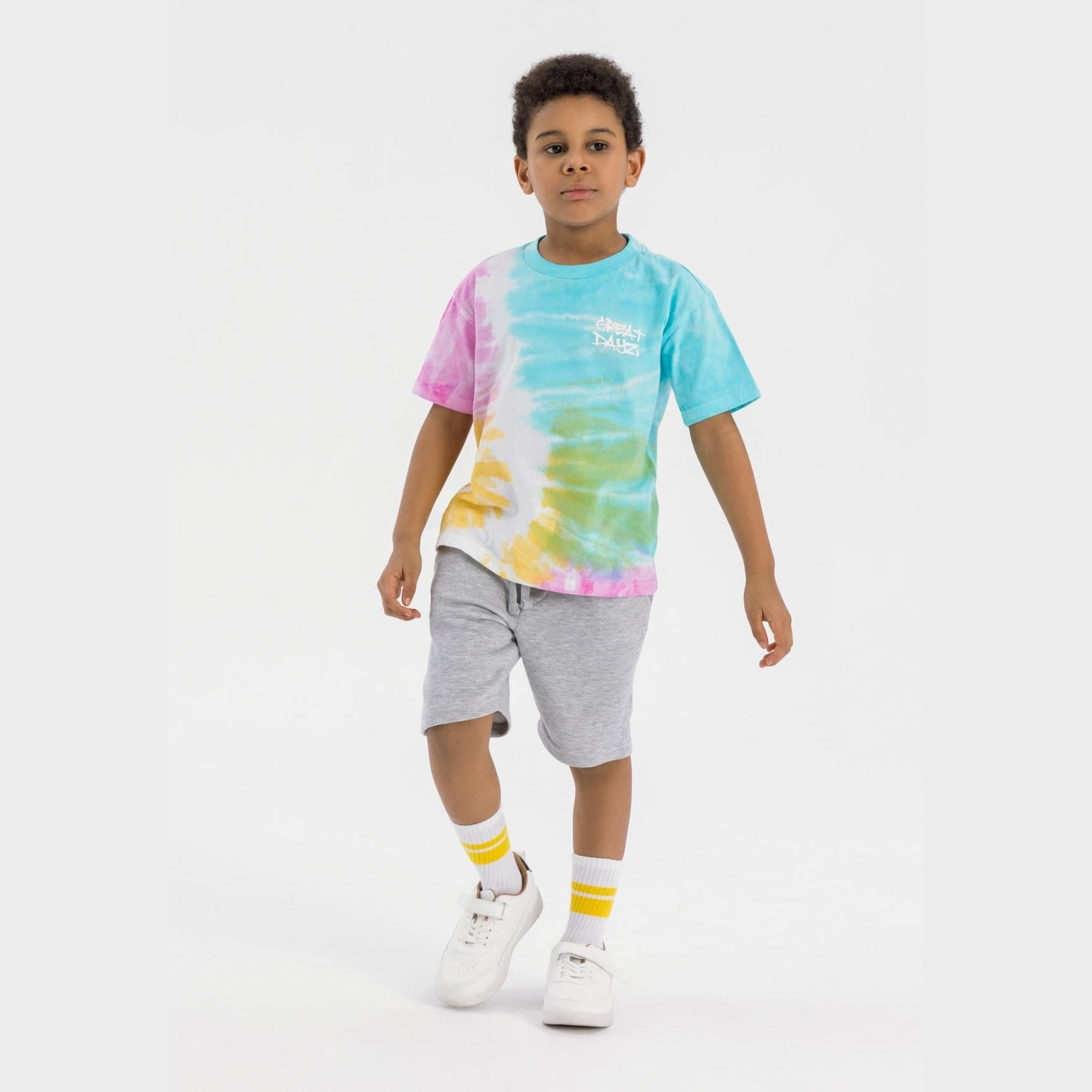 Boy wearing multicolour tie-dye t-shirt with Great Days chest print and grey fleece shorts, standing against white background