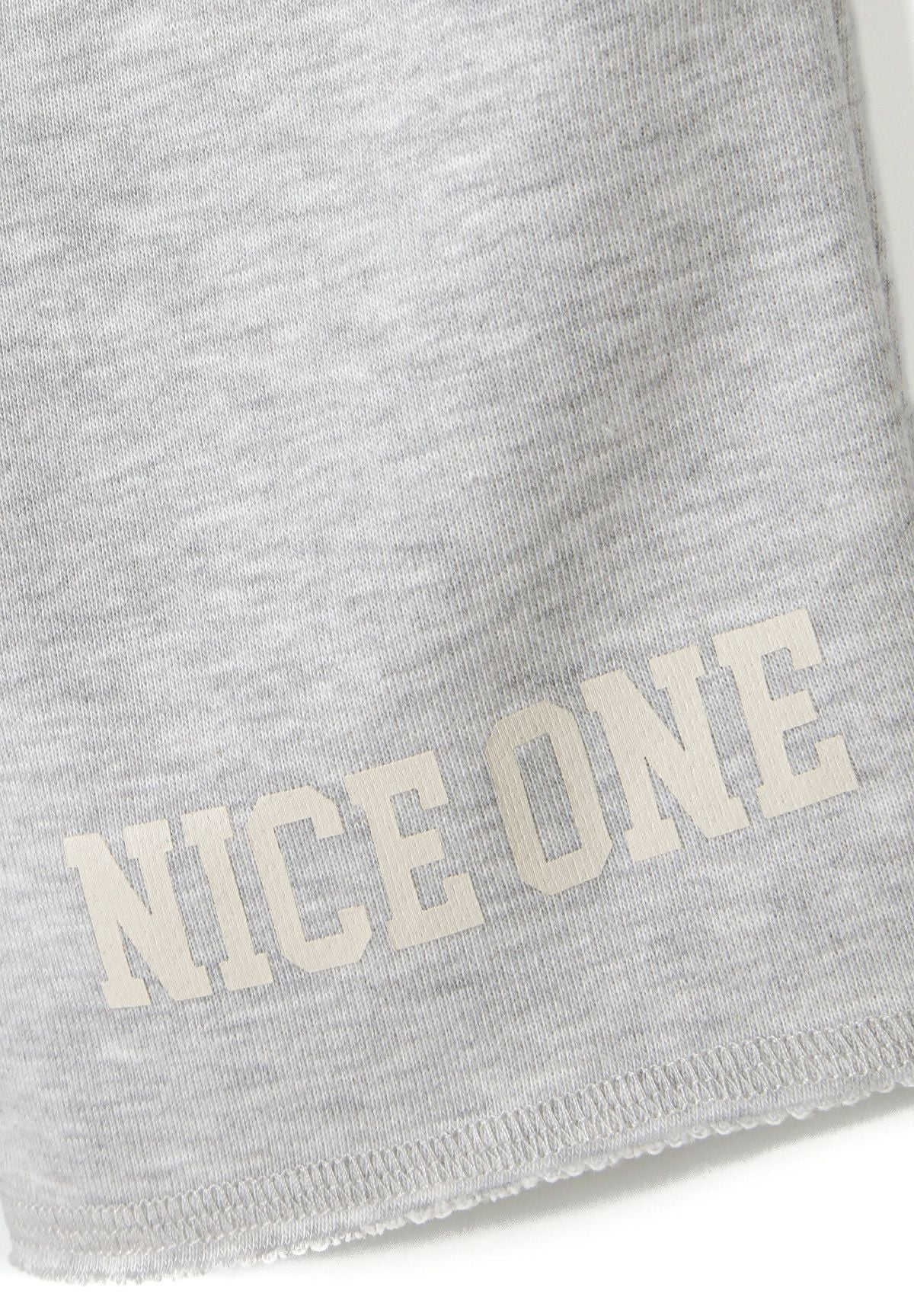 Detail of grey t-shirt with 'NICE ONE' printed text.