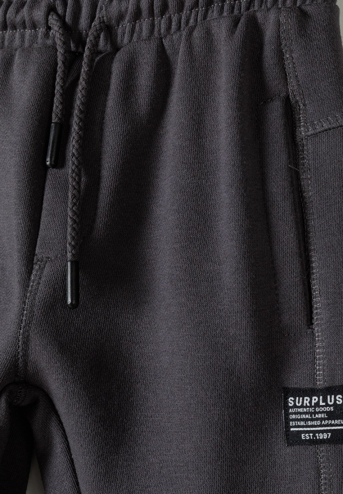 Close-up of charcoal joggers' drawcord, side pocket and SURPLUS patch.