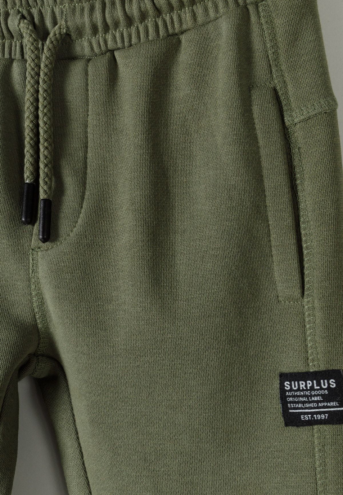Close-up of khaki joggers with elastic waistband and side pockets.