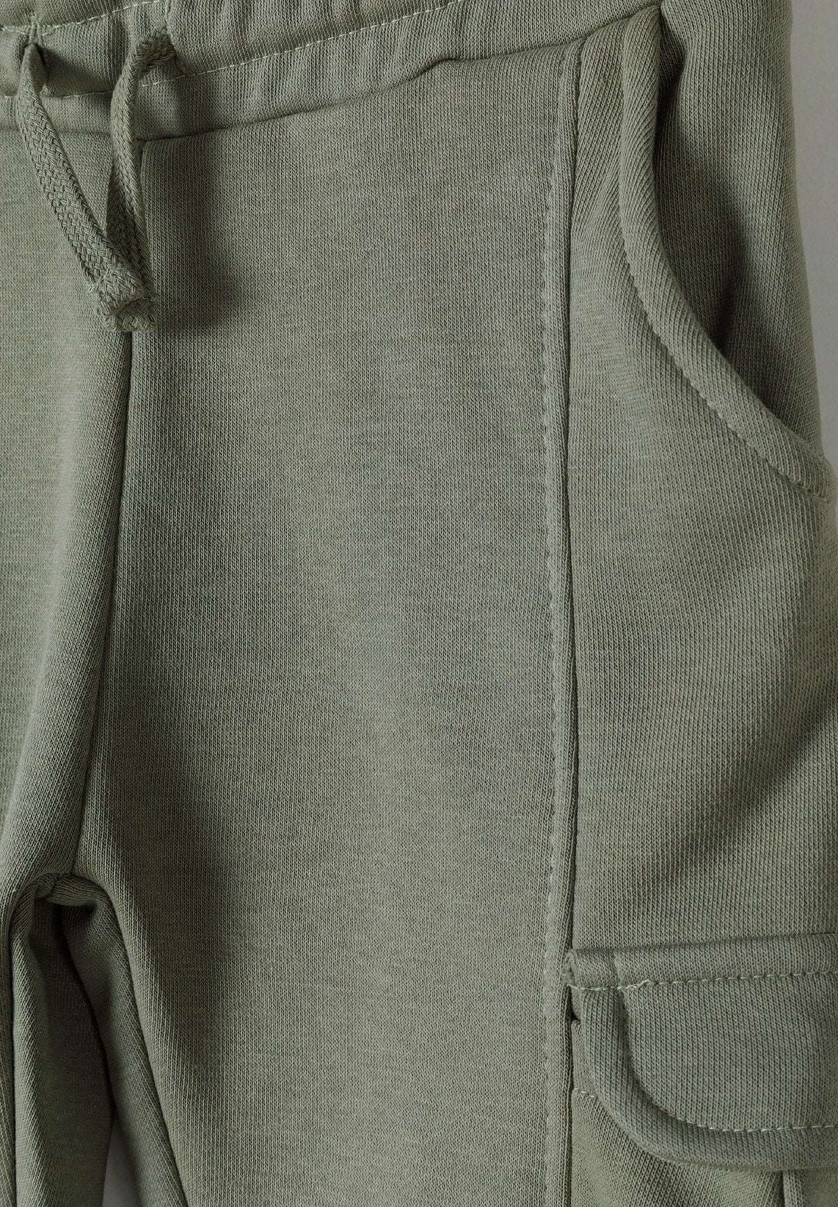 Detail of boys' khaki cargo joggers with elasticated waistband and side pockets.