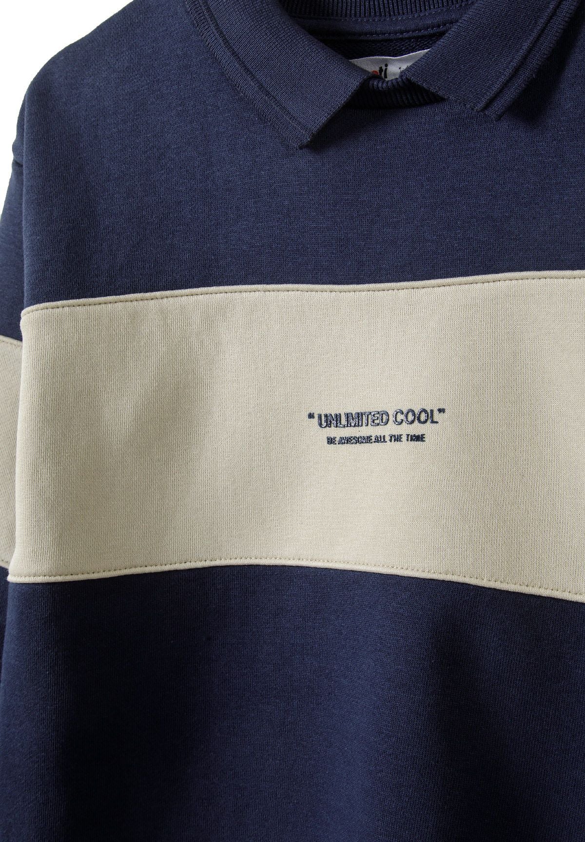 Close-up of a navy fleece jumper with a polo collar and contrasting cream panel.