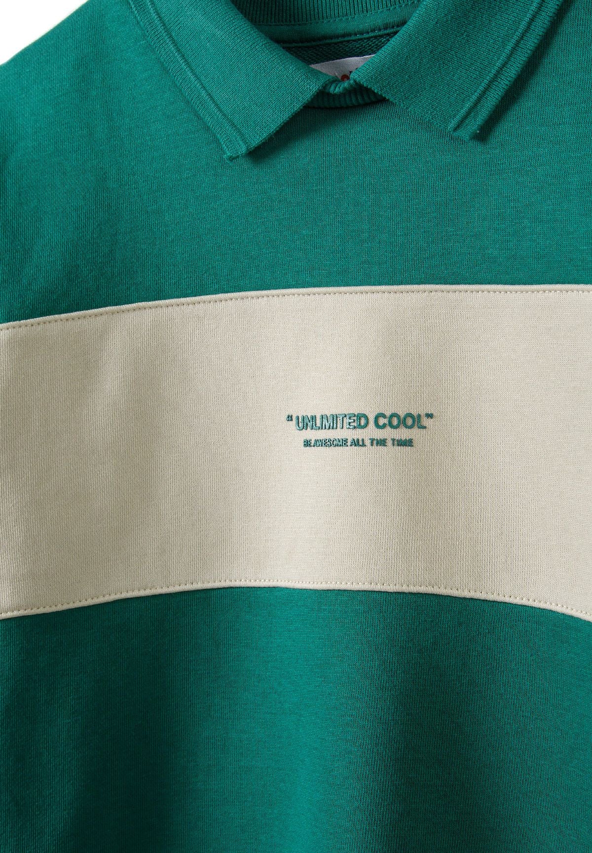 Close-up of green polo collar and UNLIMITED COOL slogan on cream chest band.