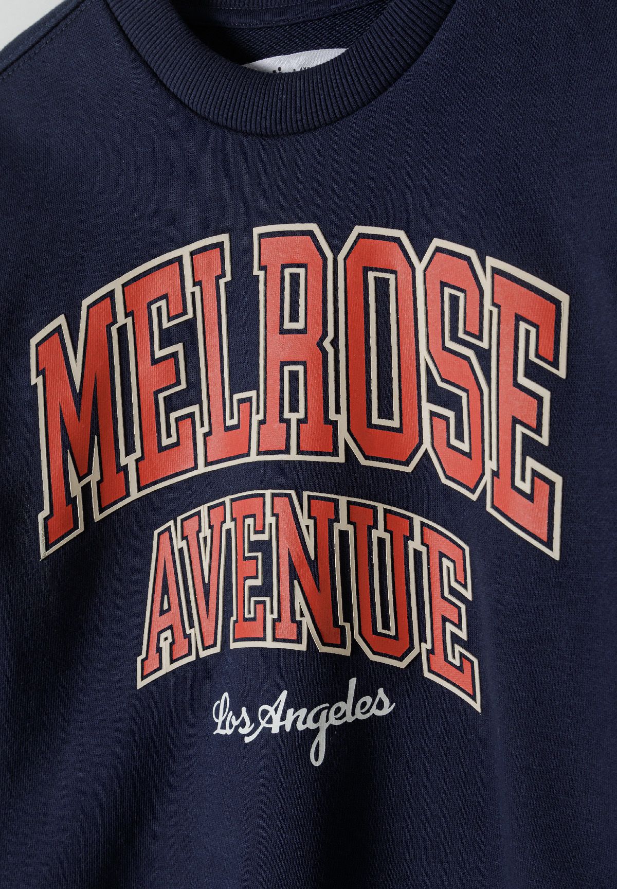 Close-up of MELROSE AVENUE Los Angeles print on navy sweatshirt.