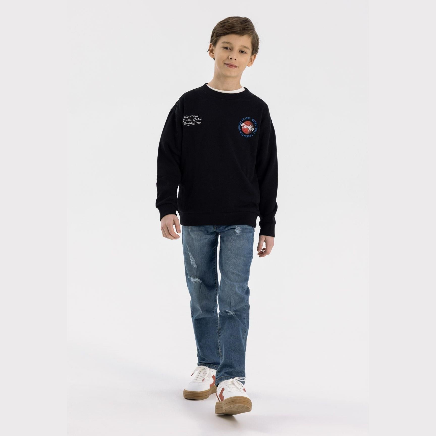 Boy wearing navy straight fit ripped jeans with black sweatshirt, full body front view on white background