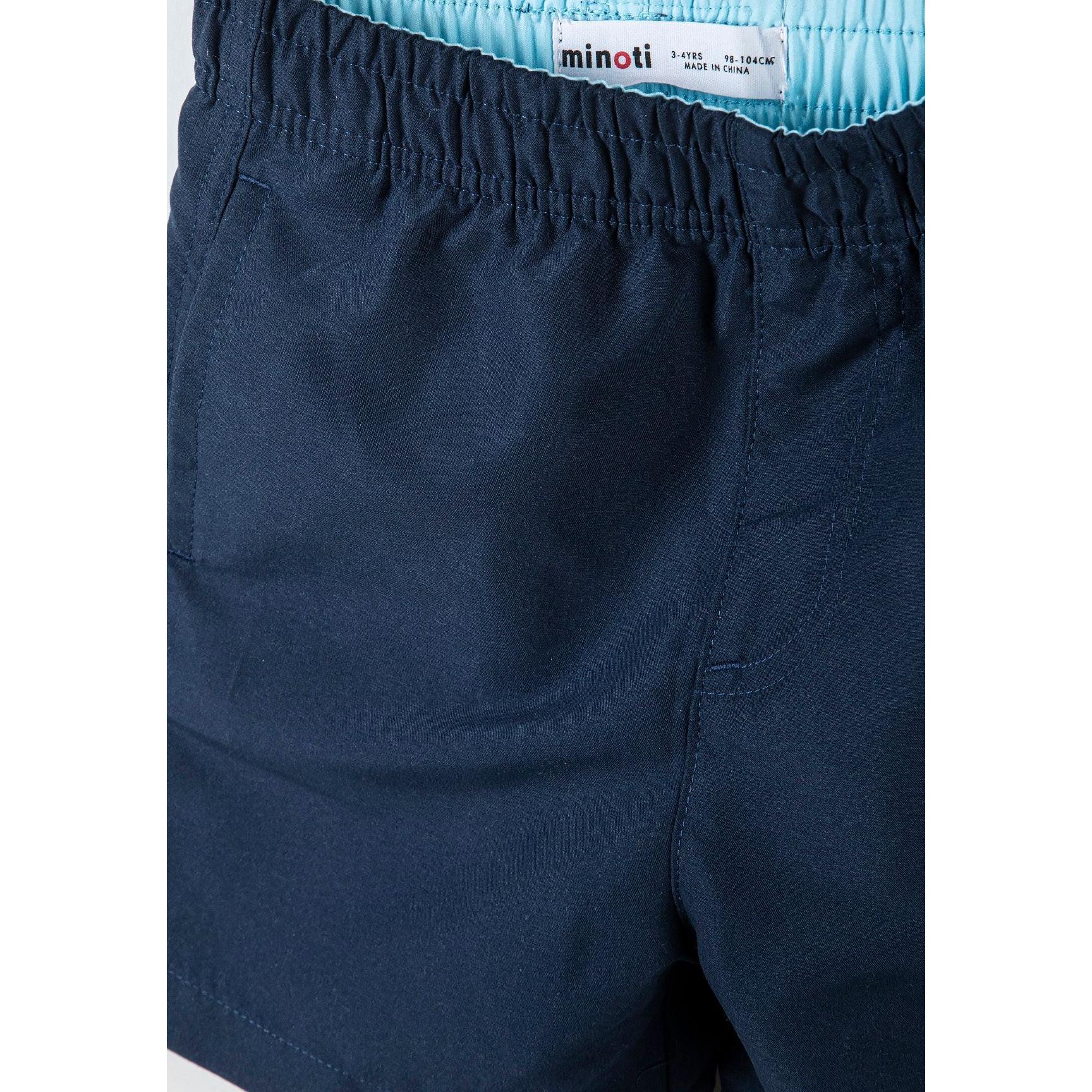 Back view of blue camouflage print swim shorts with elastic waistband showing Minoti brand label on white background