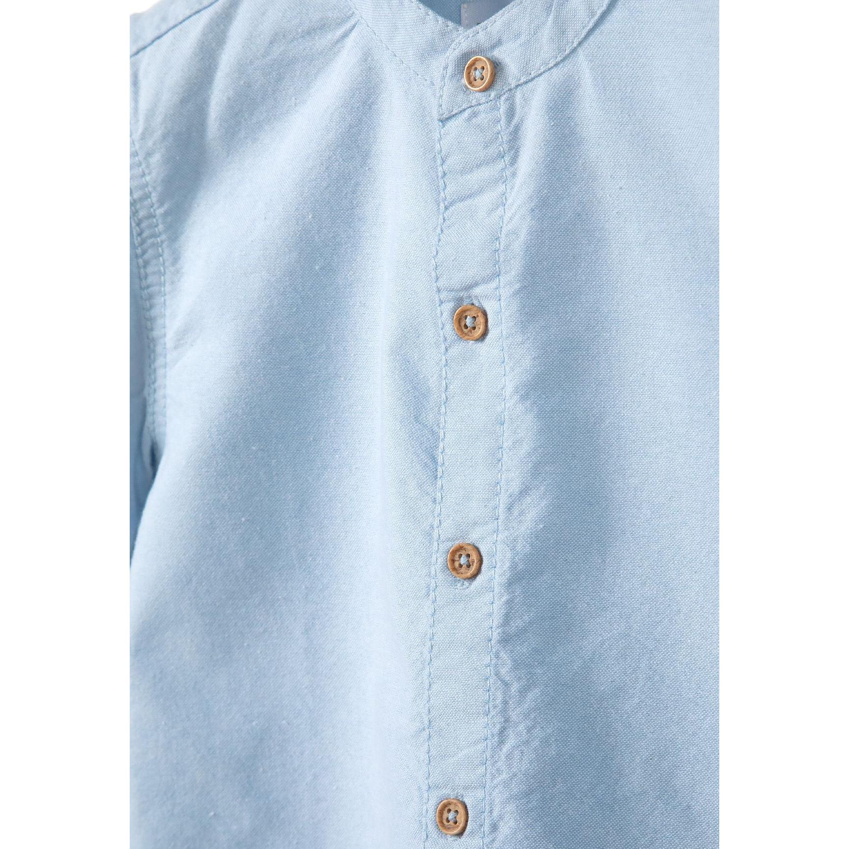 Close-up detail of stone beige chino shorts showing Minoti label, button closure and pocket construction