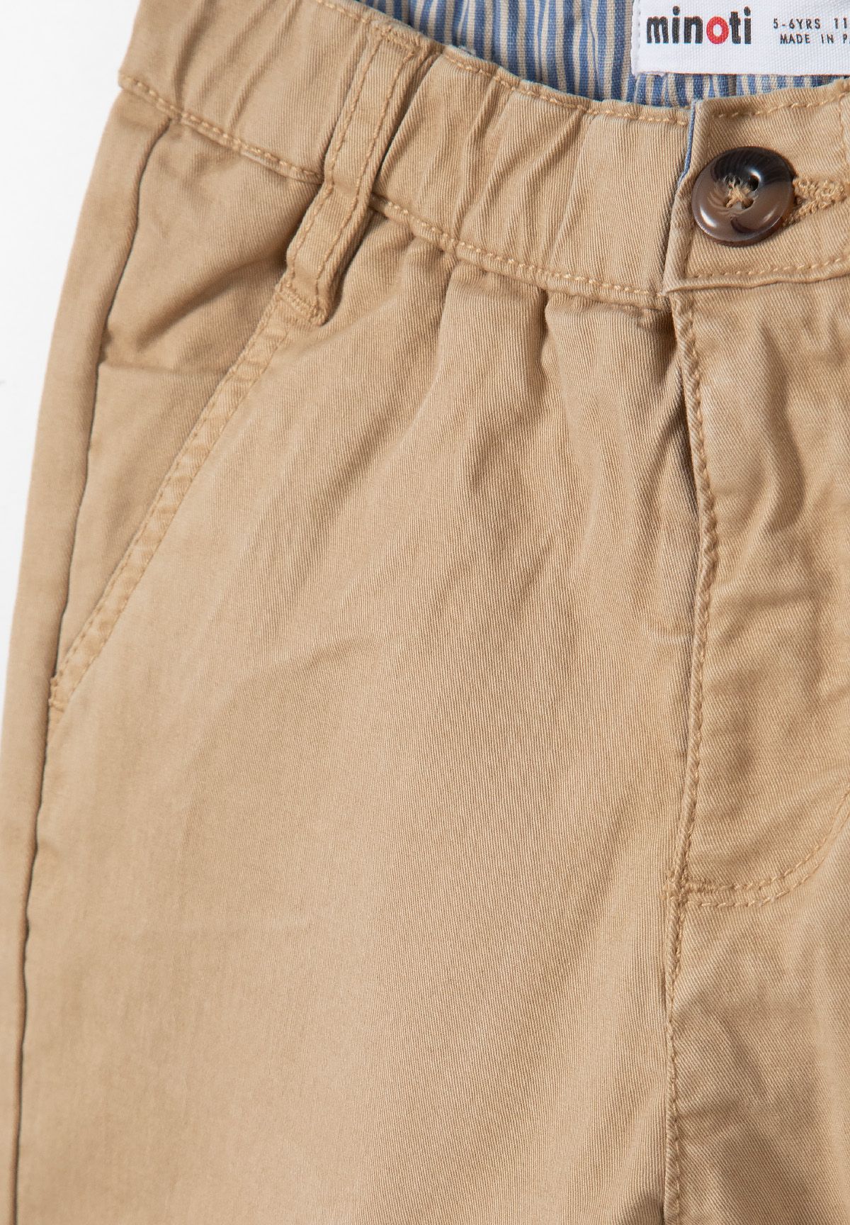 Detail of beige shorts with adjustable waistband and side pockets.