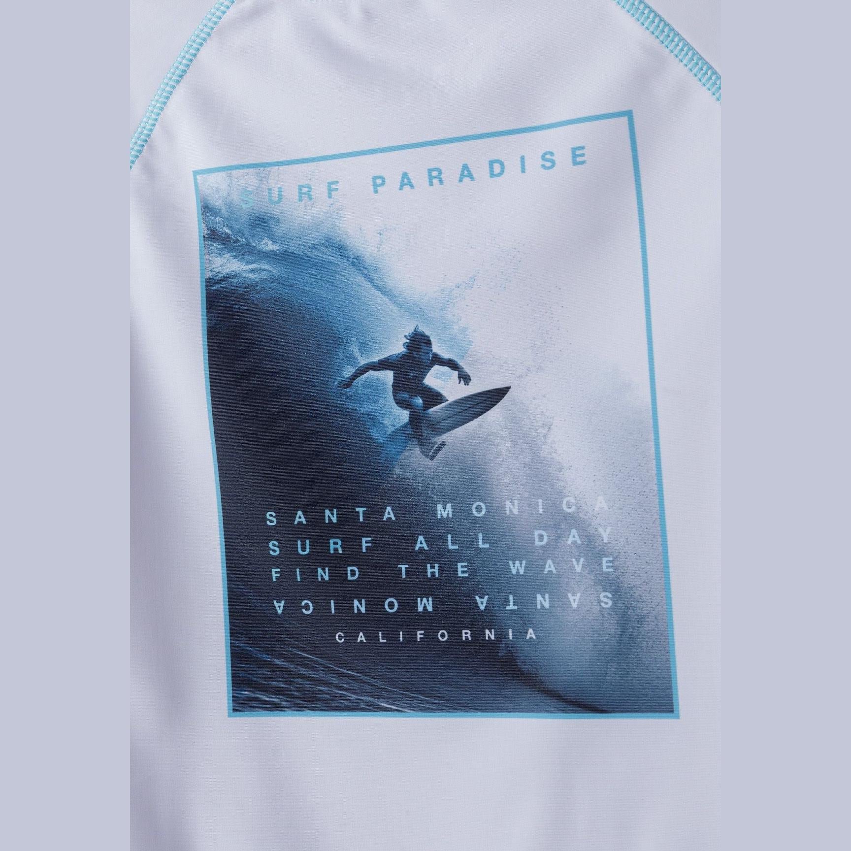 Close-up detail of surf paradise graphic print featuring surfer silhouette in ocean wave with text Santa Monica California and Find The Wave