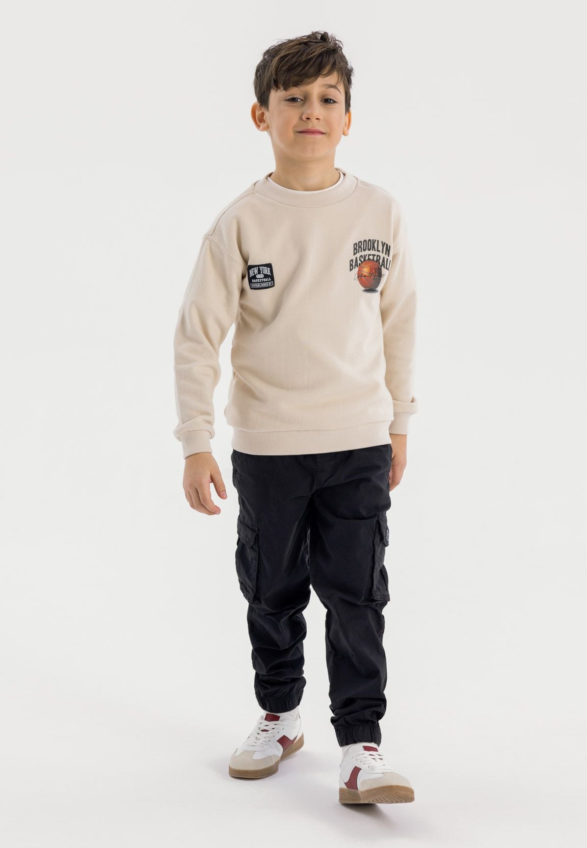 Boys black cargo trousers, front view, featuring drawcord and cargo pockets.