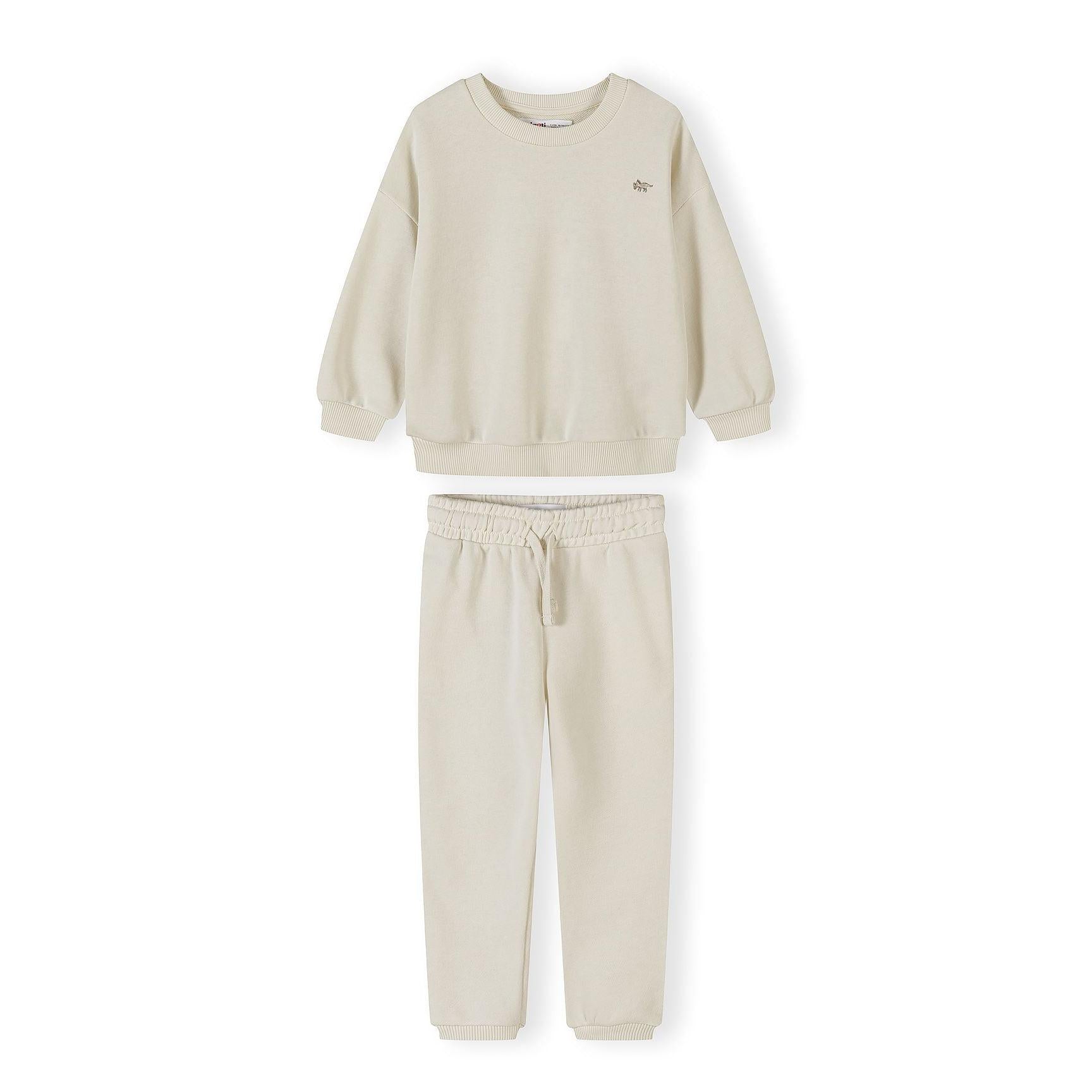 Close-up of cream tracksuit set showing sweatshirt with crew neckline and matching joggers with elasticated waist on white background