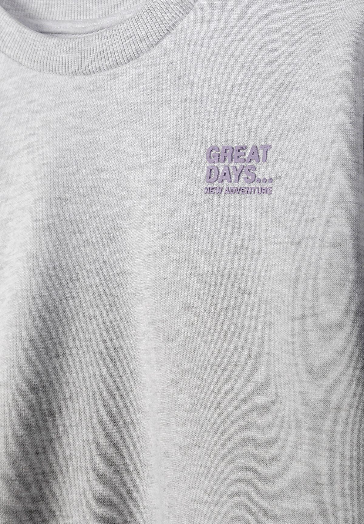 Close-up of the grey sweatshirt's lilac GREAT DAYS NEW ADVENTURE chest print.