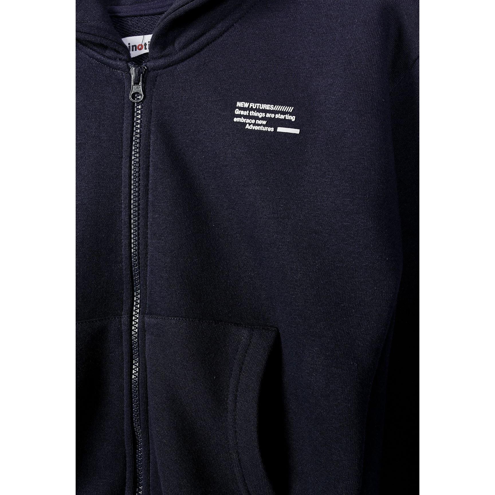 Close-up detail of navy hoodie showing zip fastening and small white text print on chest area
