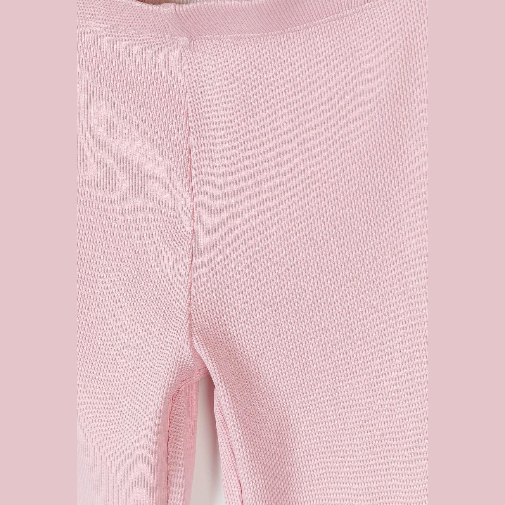 Close-up detail of pink ribbed leggings showing texture and scalloped hem edge