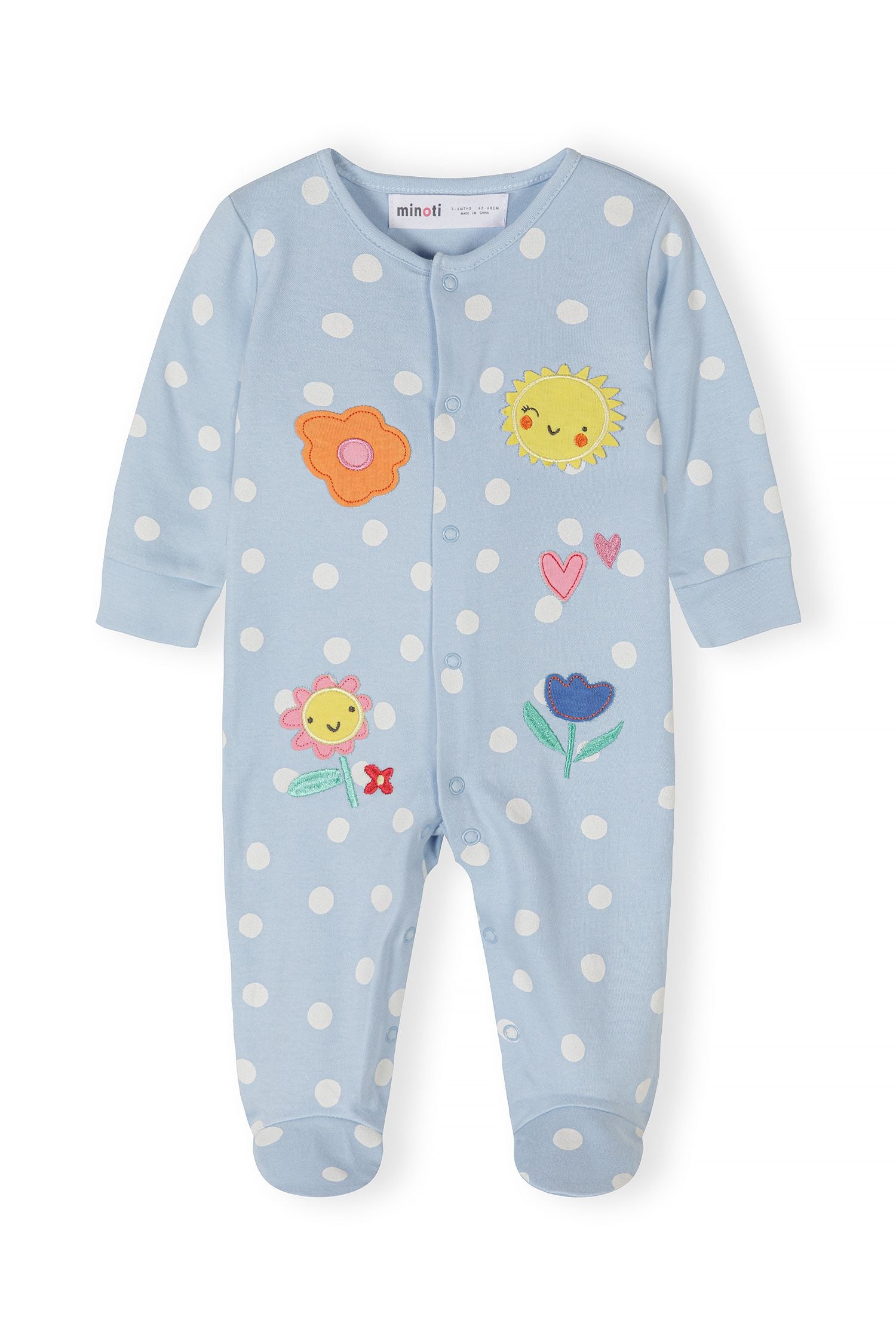 Close-up of a blue polka dot sleepsuit for girls with floral embroidery and press studs.